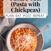 A gray bowl is piled with a orange-red pasta with chickpeas and grated Parmesan cheese. A white text box at the top of the image includes the words, "cozy one pot pasta e ceci (pasta with chickpeas)" and "plan. eat. post. repeat."