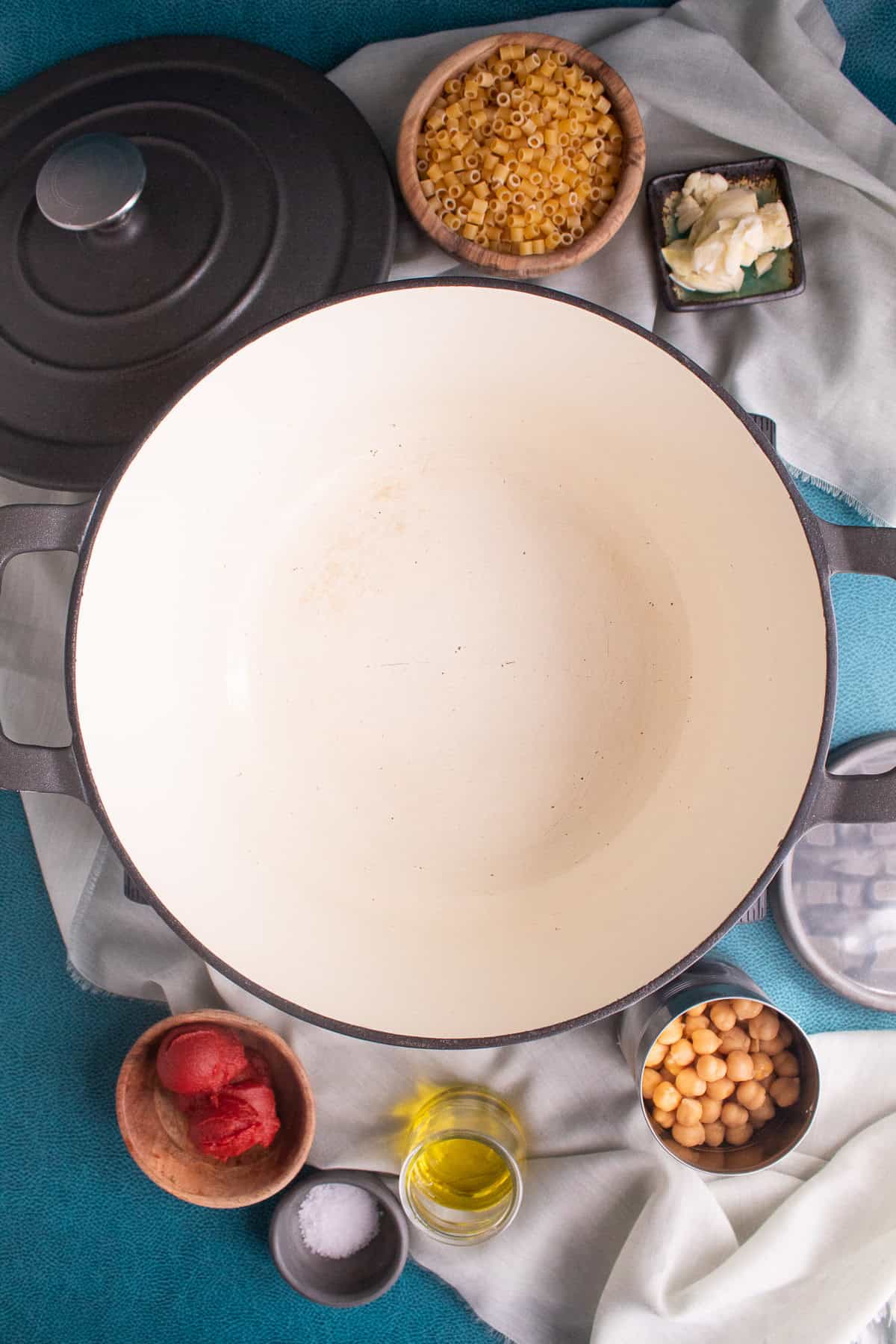 A large enameled cast iron pot is heated and small bowls with the remaining ingredients sit nearby.