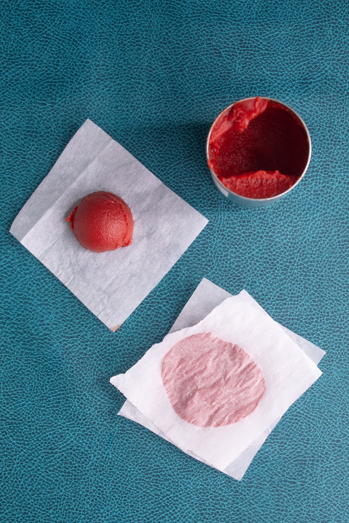 Tablespoons of tomato paste are stored between squares of parchment paper for freezer storage.