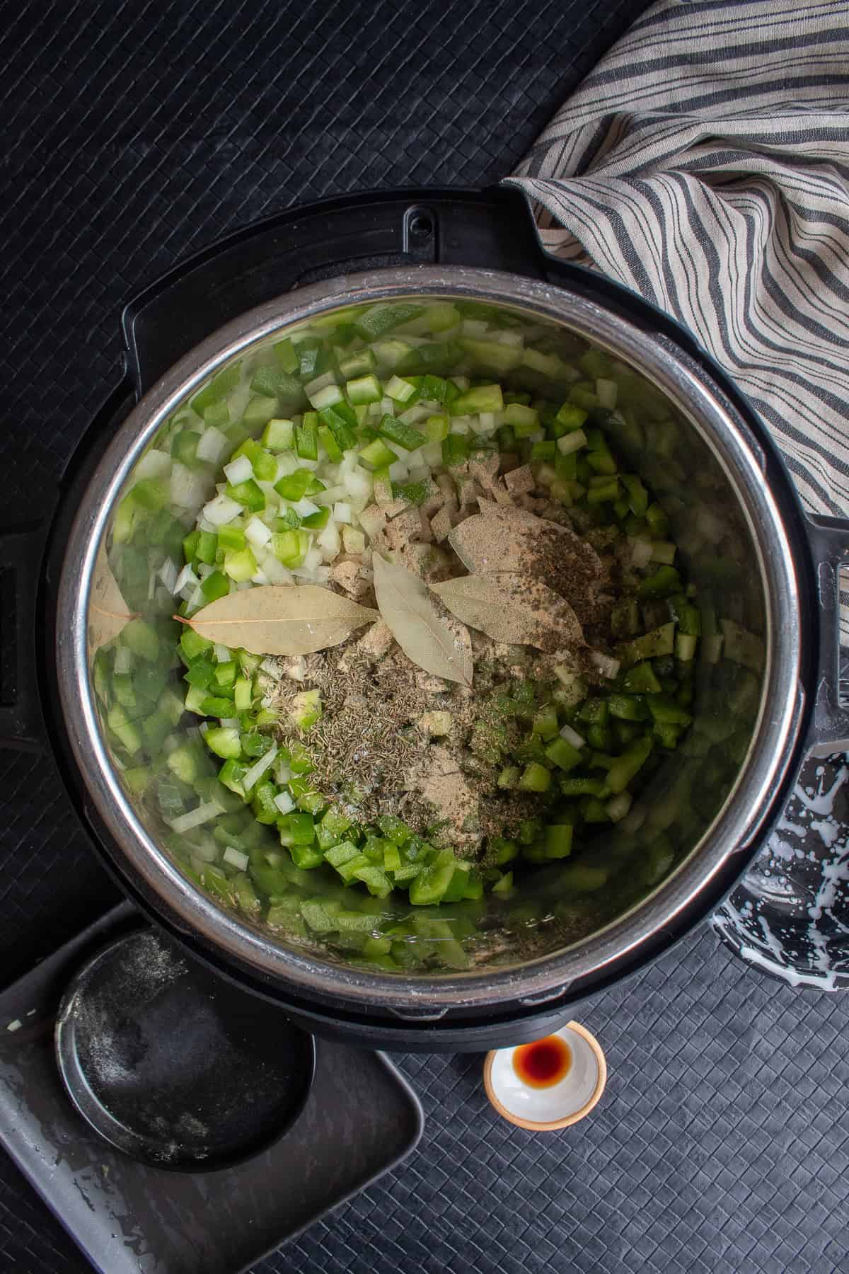 Spices are sprinkled over the top of the vegetables in the pot.