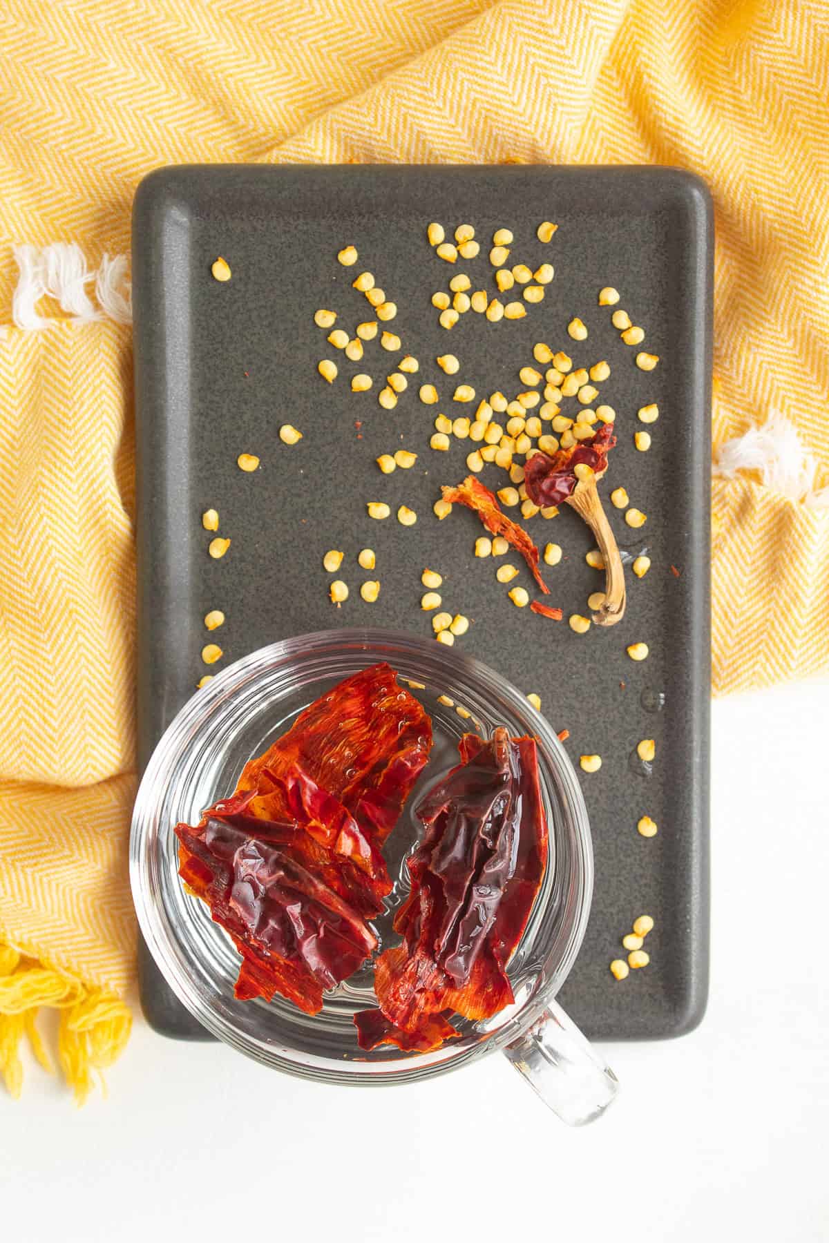 Pieces of the seeded and stemmed dried chile are added to water in a coffee mug.