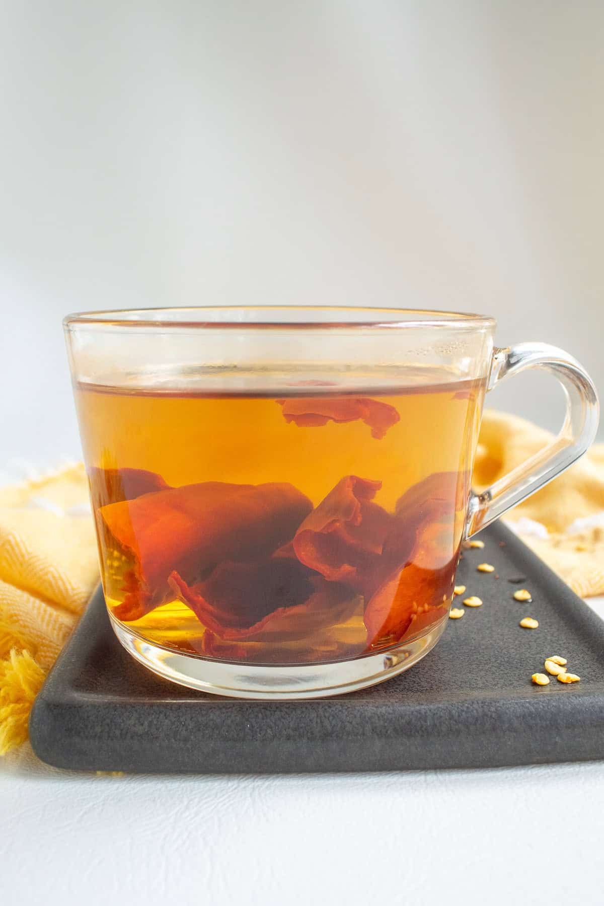 The pieces of dried guajillo chile are softened in the boiling water in a clear coffee cup.