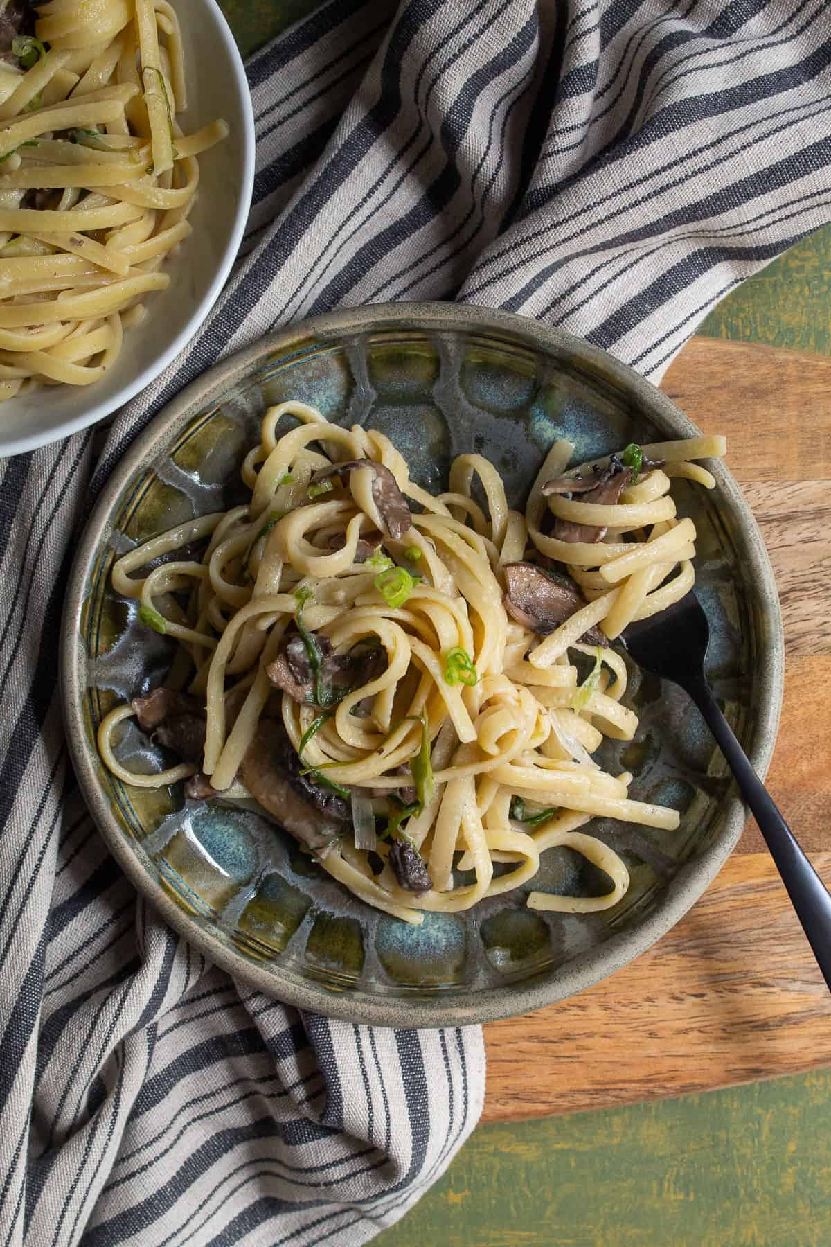 A serving of pasta sits on a green and gray patterned plate.