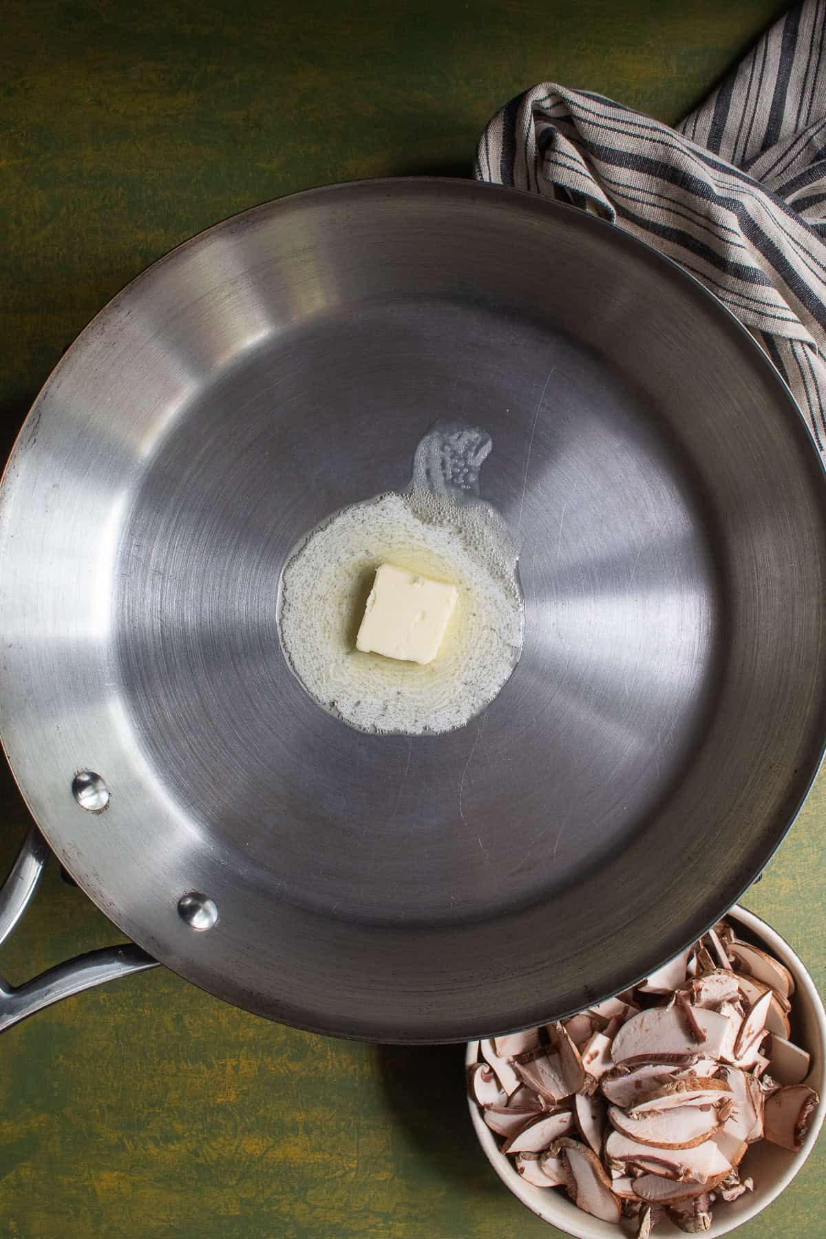 A tablespoon of butter melts in the bottom of a stainless steel skillet.