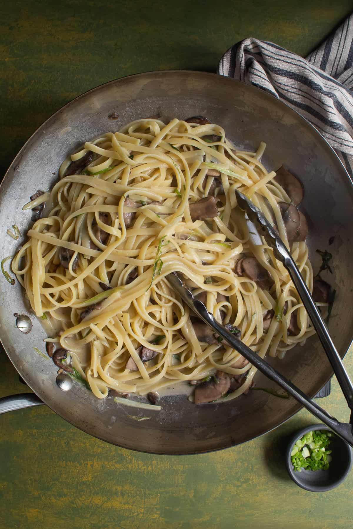 Pasta with mushrooms and scallions in a pan.