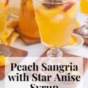 Glasses of the golden sangria garnished with star anise and peach slices. A white text box at the bottom of the image contains the words, "peach sangria with star anise syrup" and "plan. eat. post. repeat."