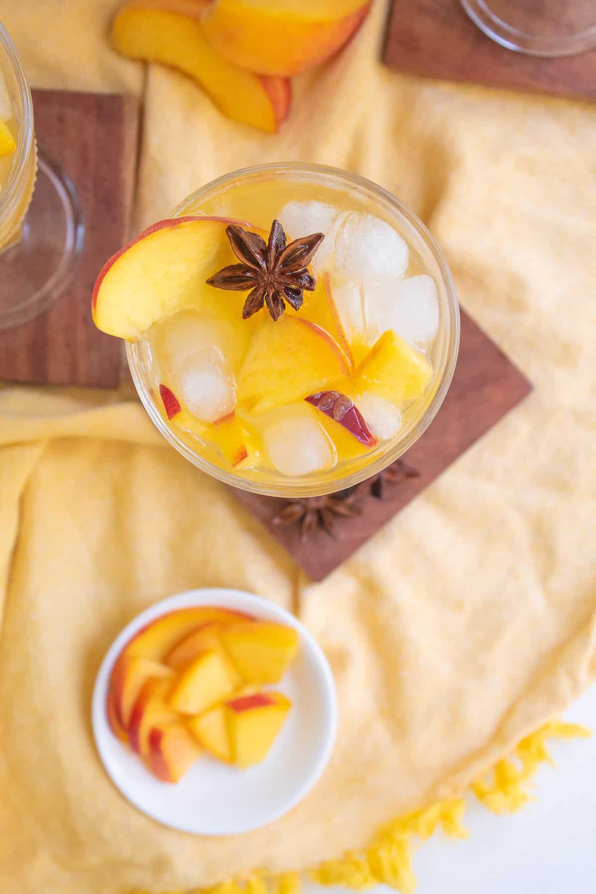 A detail image of the top of a glass of sangria with the star anise pod and sliced peach visible.