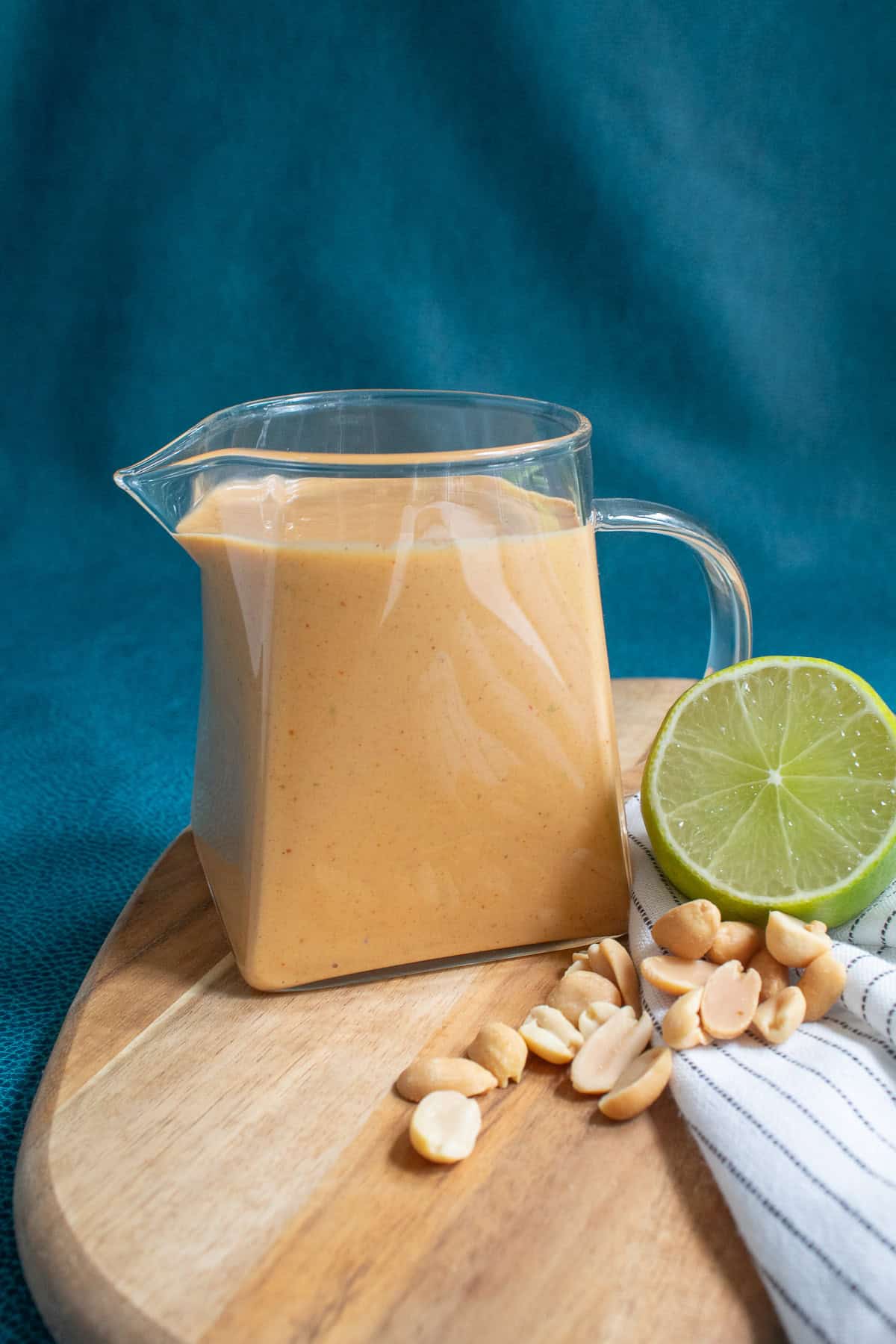 Peanut sauce is served in a small glass pitcher.