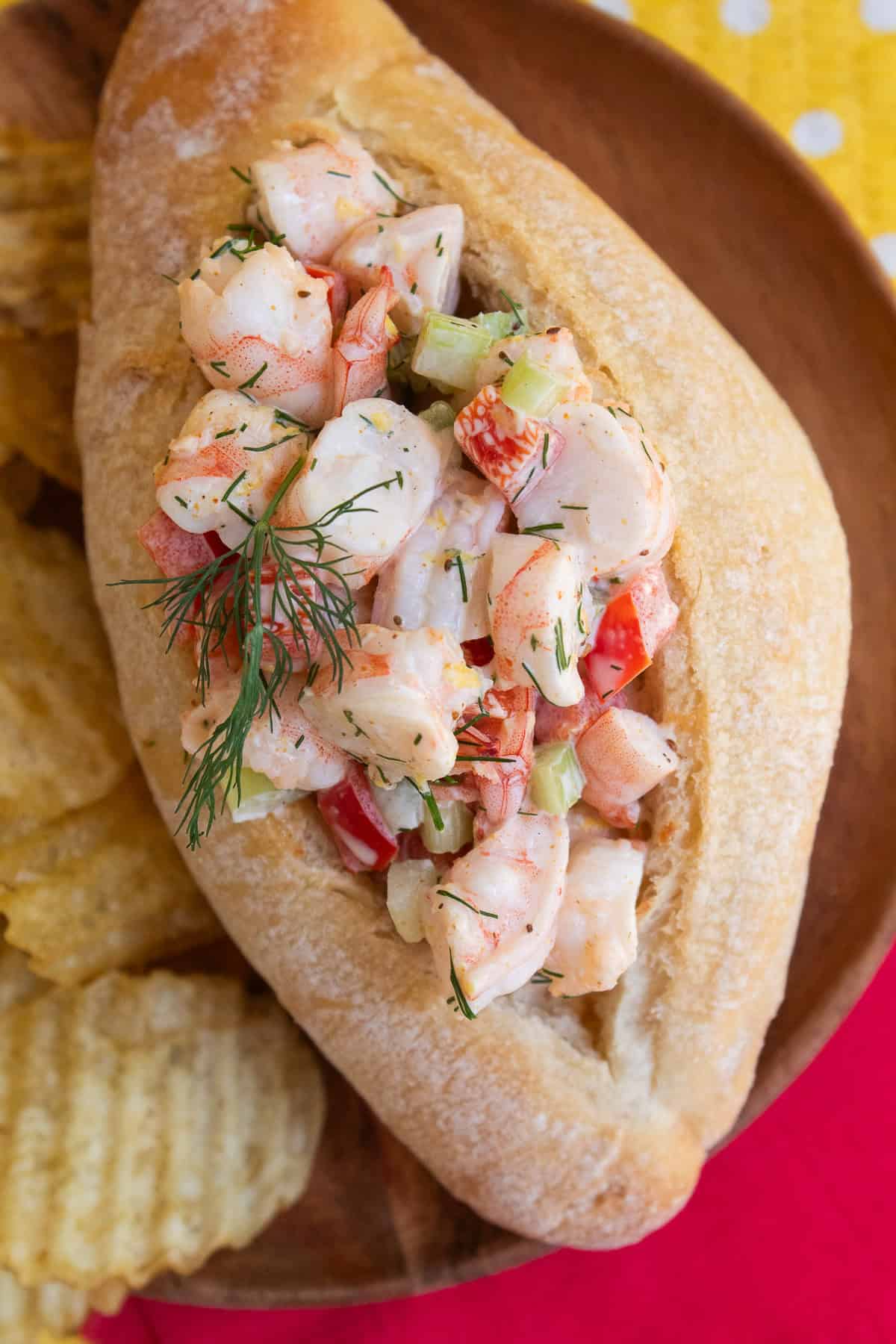 A shrimp roll is filled with shrimp salad and garnished with dill.