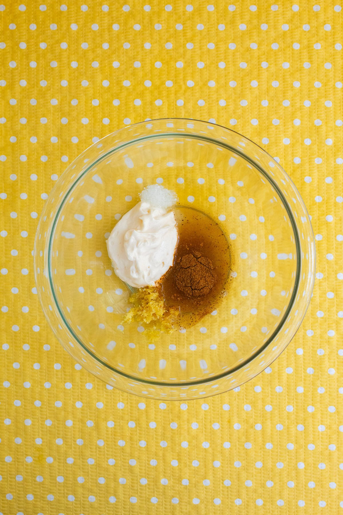 Mayonnaise, seasoning, lemon zest, and juice are added to a glass bowl.