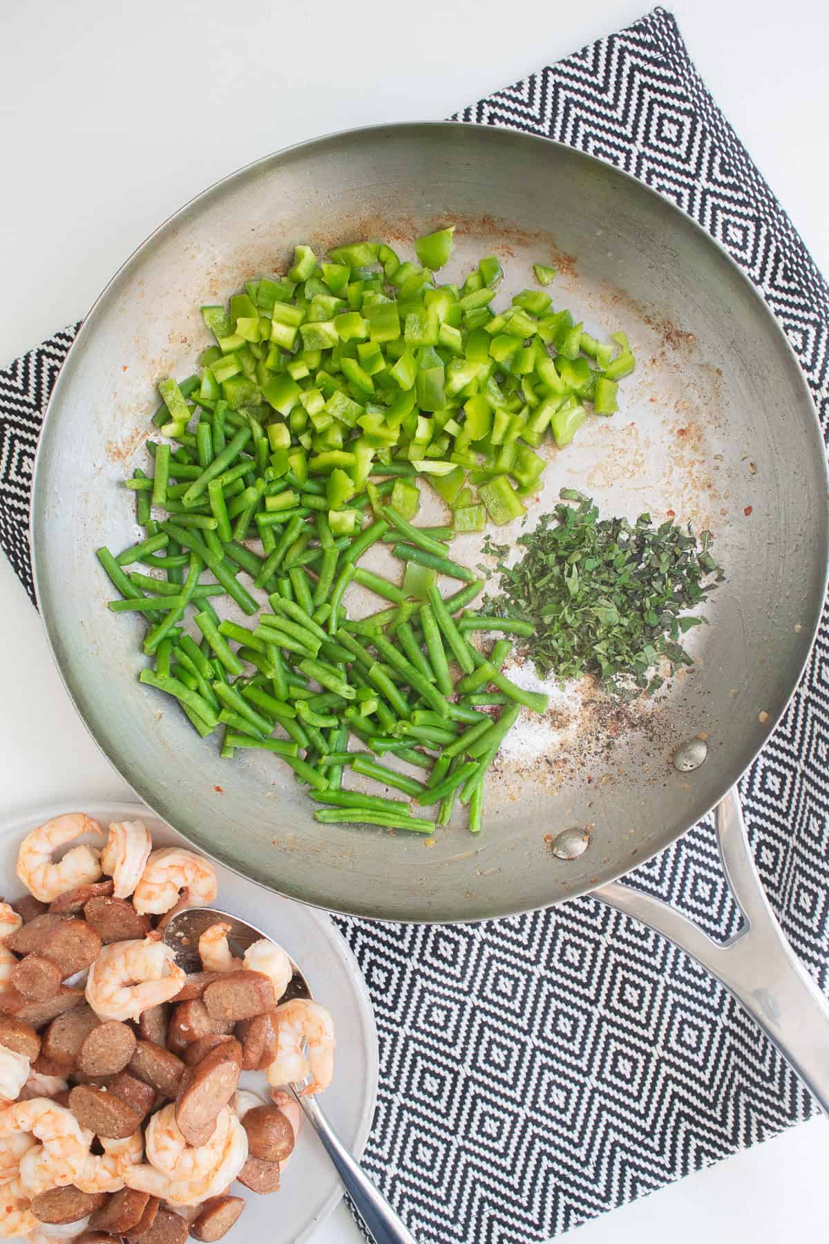 Bell peppers, oregano, and green beans are added to the skillet.