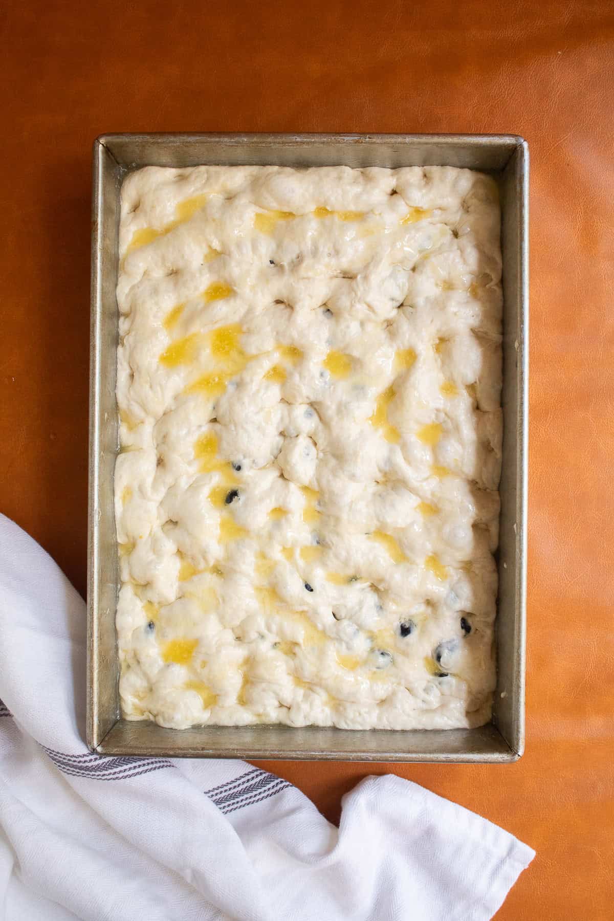 Melted butter is drizzled over the surface of the unbaked dough.