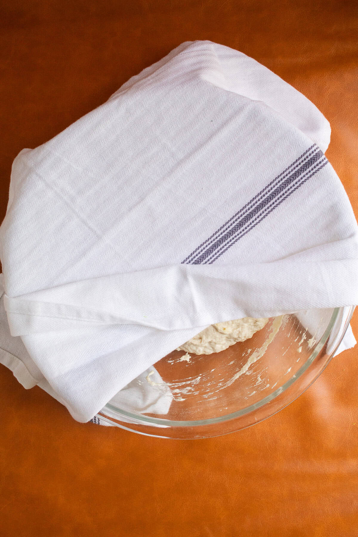 The dough is covered up with a clean kitchen towel.