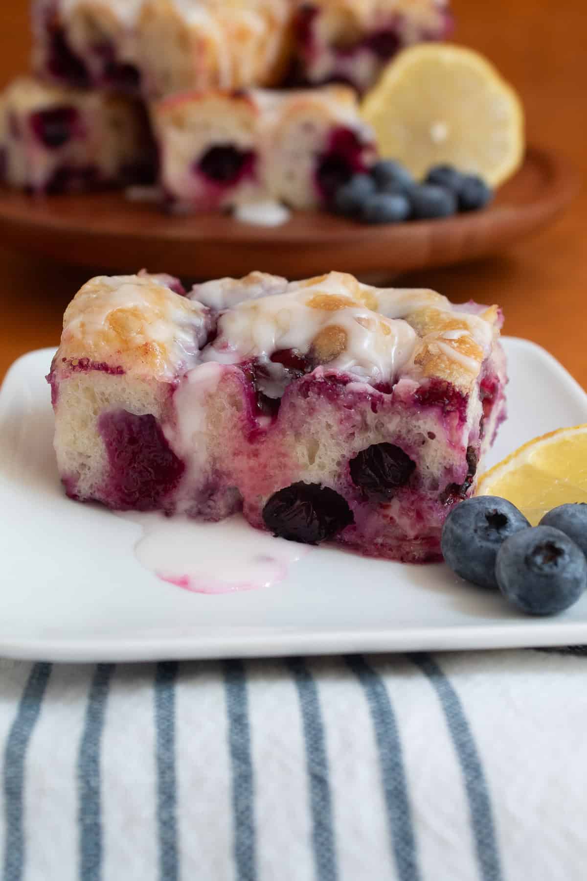 A slice of the sweet focaccia shows jammy berries and satiny lemon glaze.