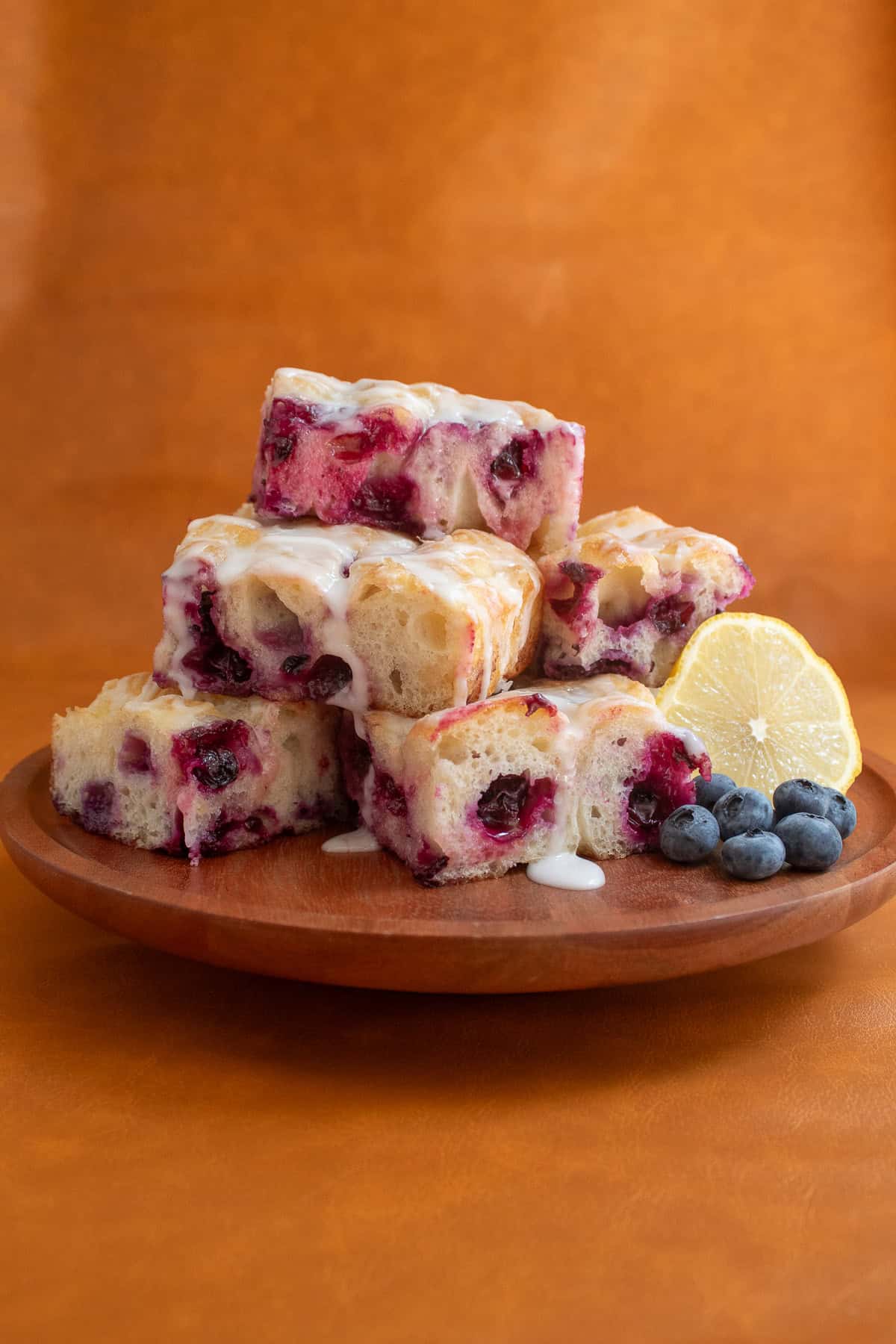 Slices of sweet focaccia are piled up on a wood cake plate.