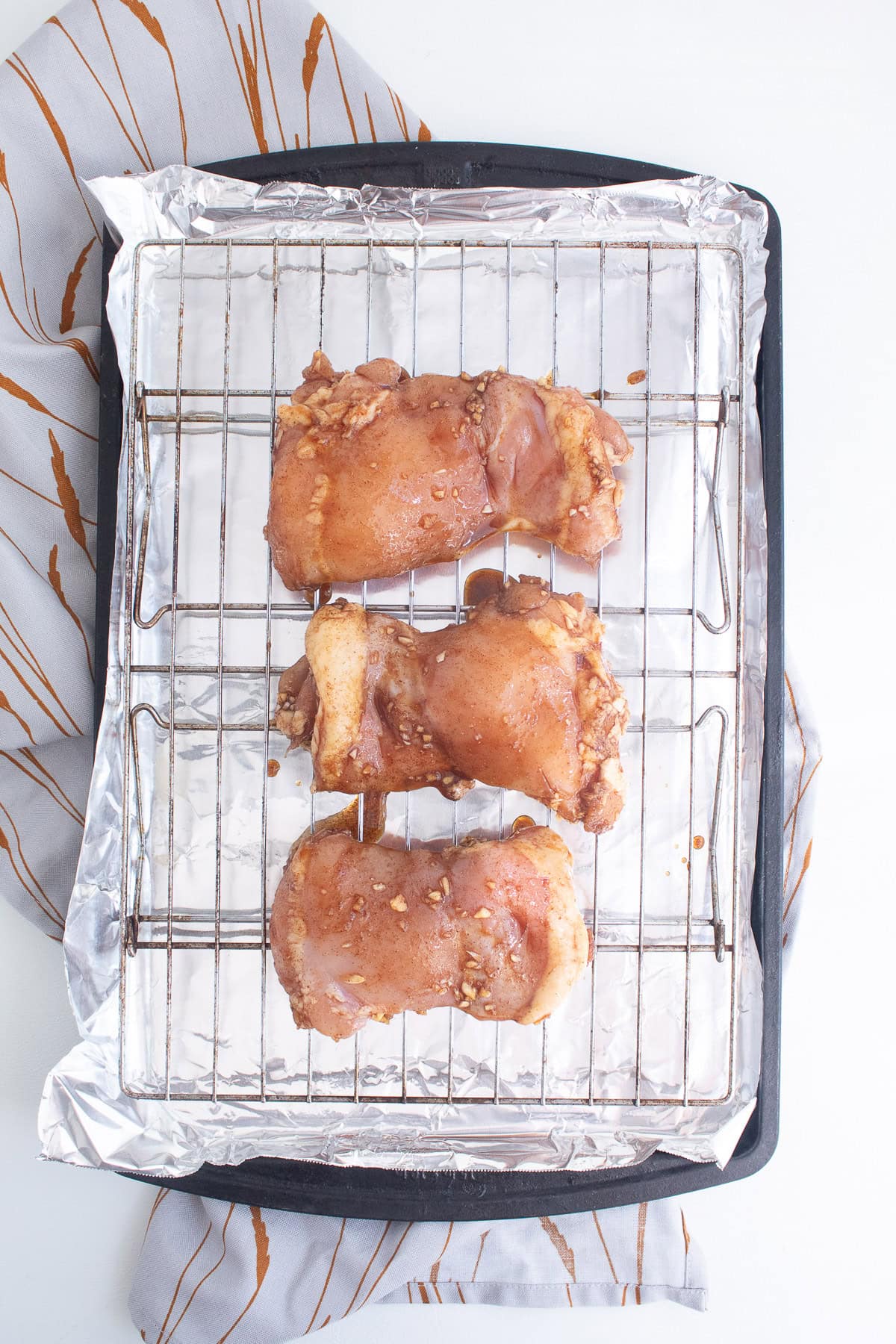 The marinated chicken thighs are spread out over the wire rack.