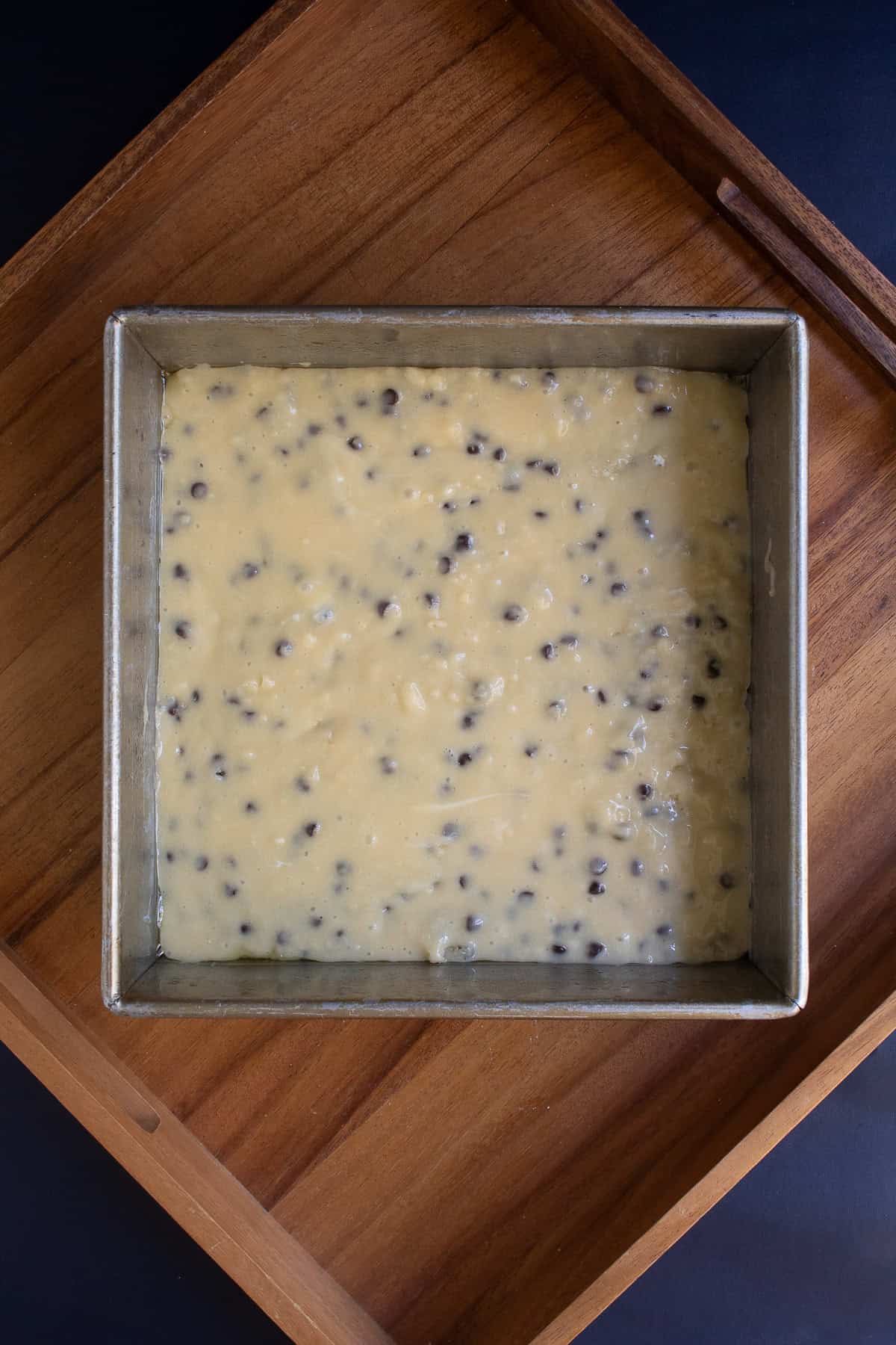 A thin layer of coffee cake batter is spread over the bottom of a square pan.