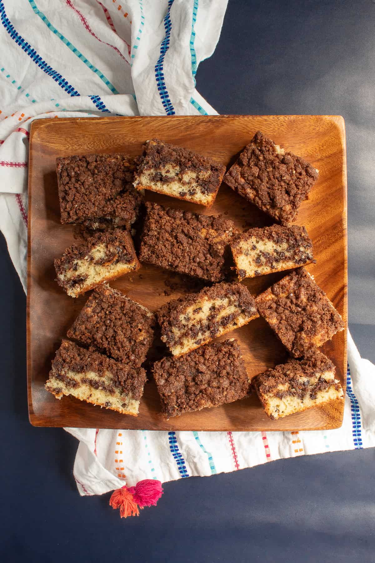 Slices of coffee cake are arranged on a square wood platter.