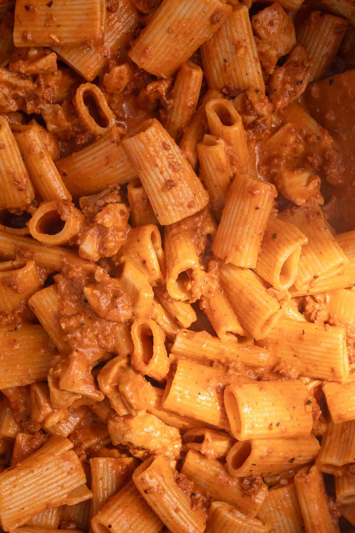 A detail image of the glossy pasta with chinks of chicken and ground chorizo.
