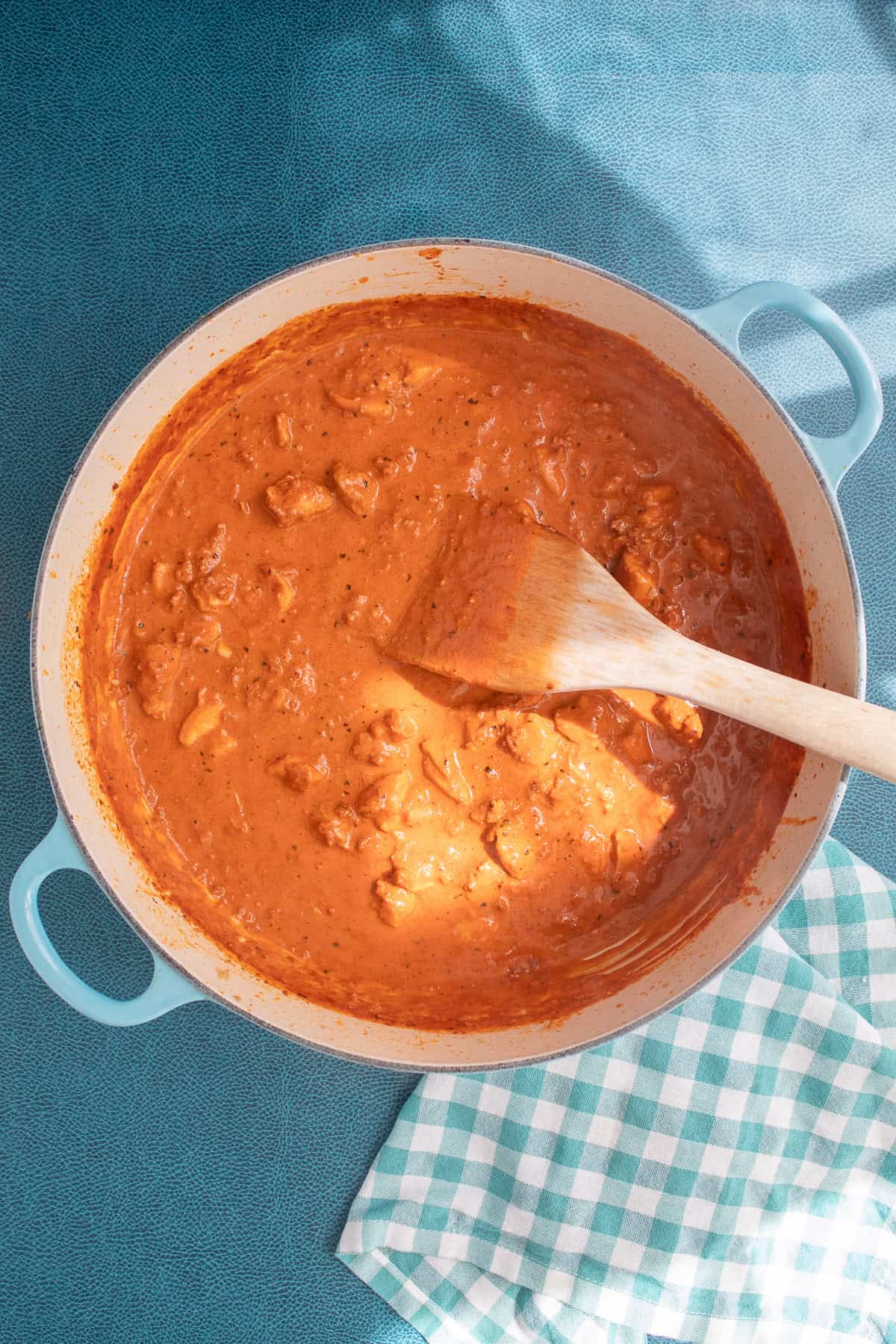 The golden orange sauce coats chunks of chicken in a wide pot.