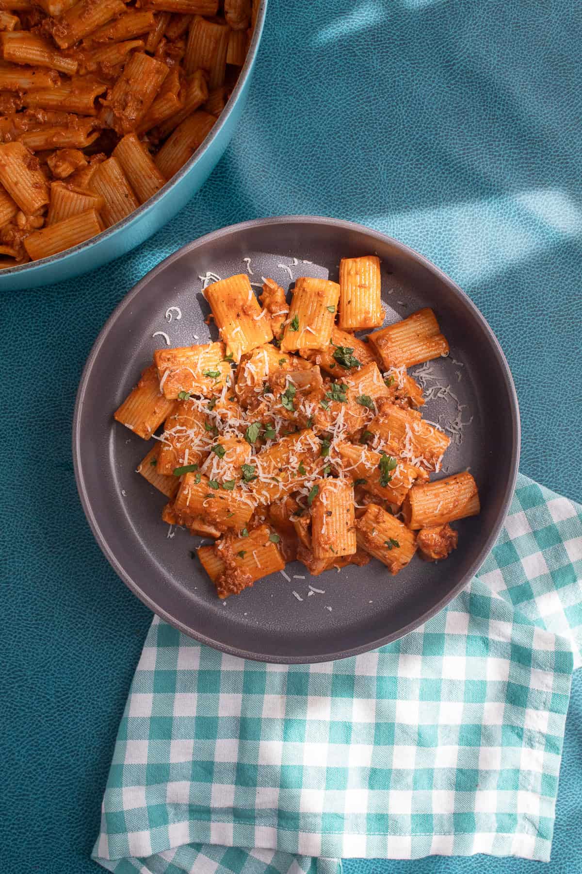 A serving of chorizo chicken pasta is garnished with shredded Parmesan and chopped cilantro.