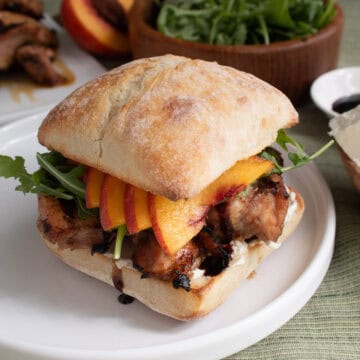 The chicken and peach sandwich is on a toasted ciabatta bun with arugula and goat cheese.