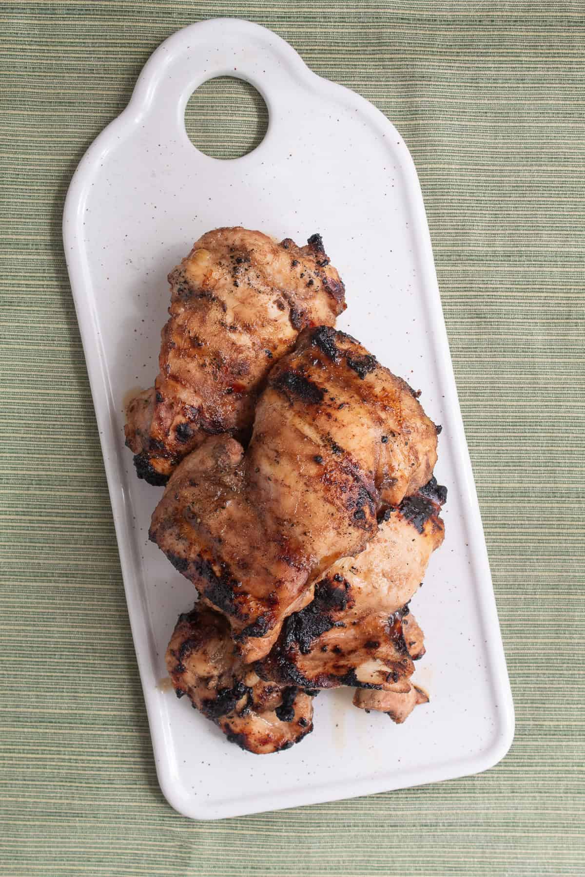 Grilled honey balsamic chicken thighs rest on a platter.
