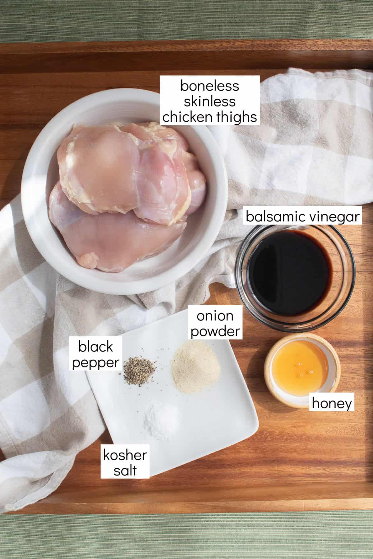 Ingredients for the balsamic vinegar chicken marinade are displayed and labeled with white text boxes including the words boneless skinless chicken thighs, balsamic vinegar, honey, onion powder, black pepper, and kosher salt.