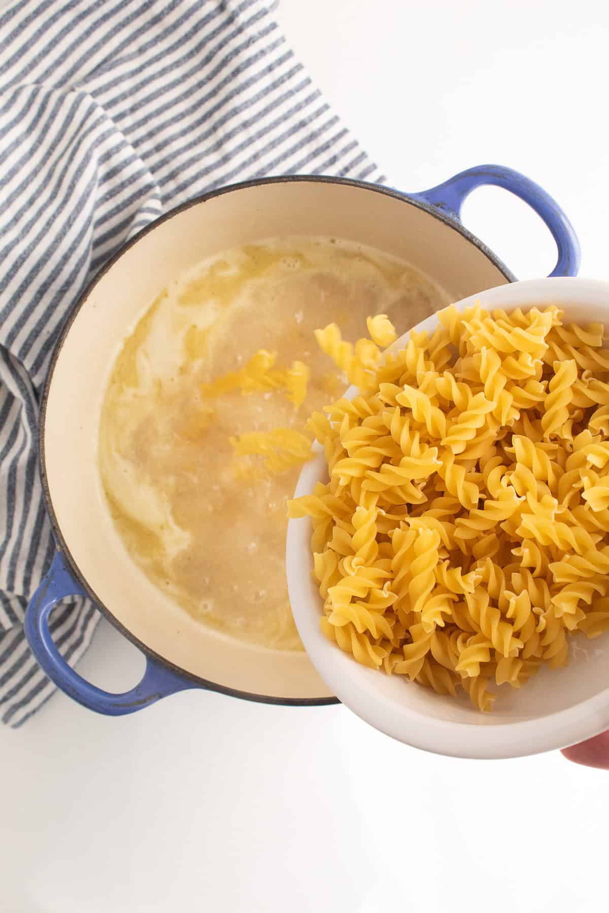 The dry pasta is added to the boiling chicken stock.