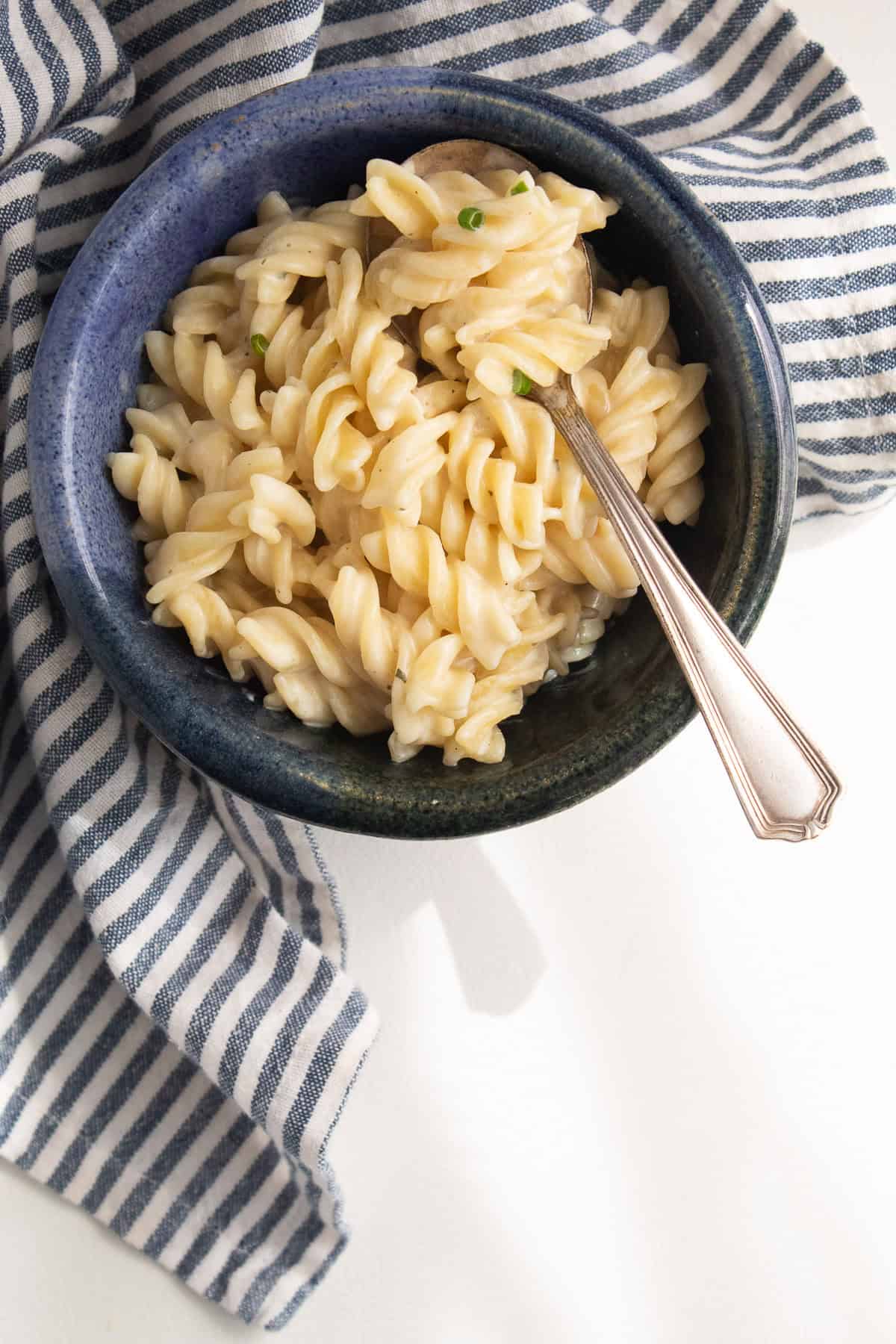 A bowl of creamy pasta with a silver spoon.