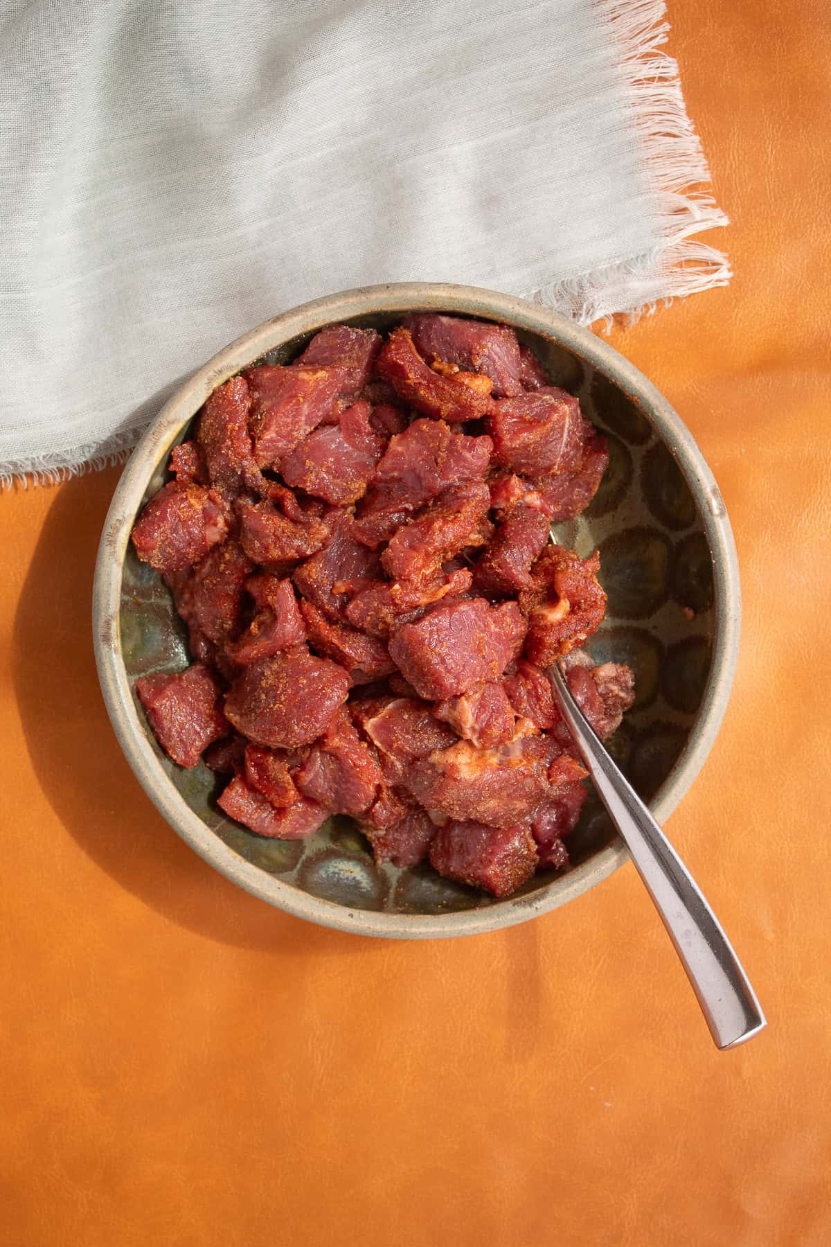 The marinated lamb is coated with spices.