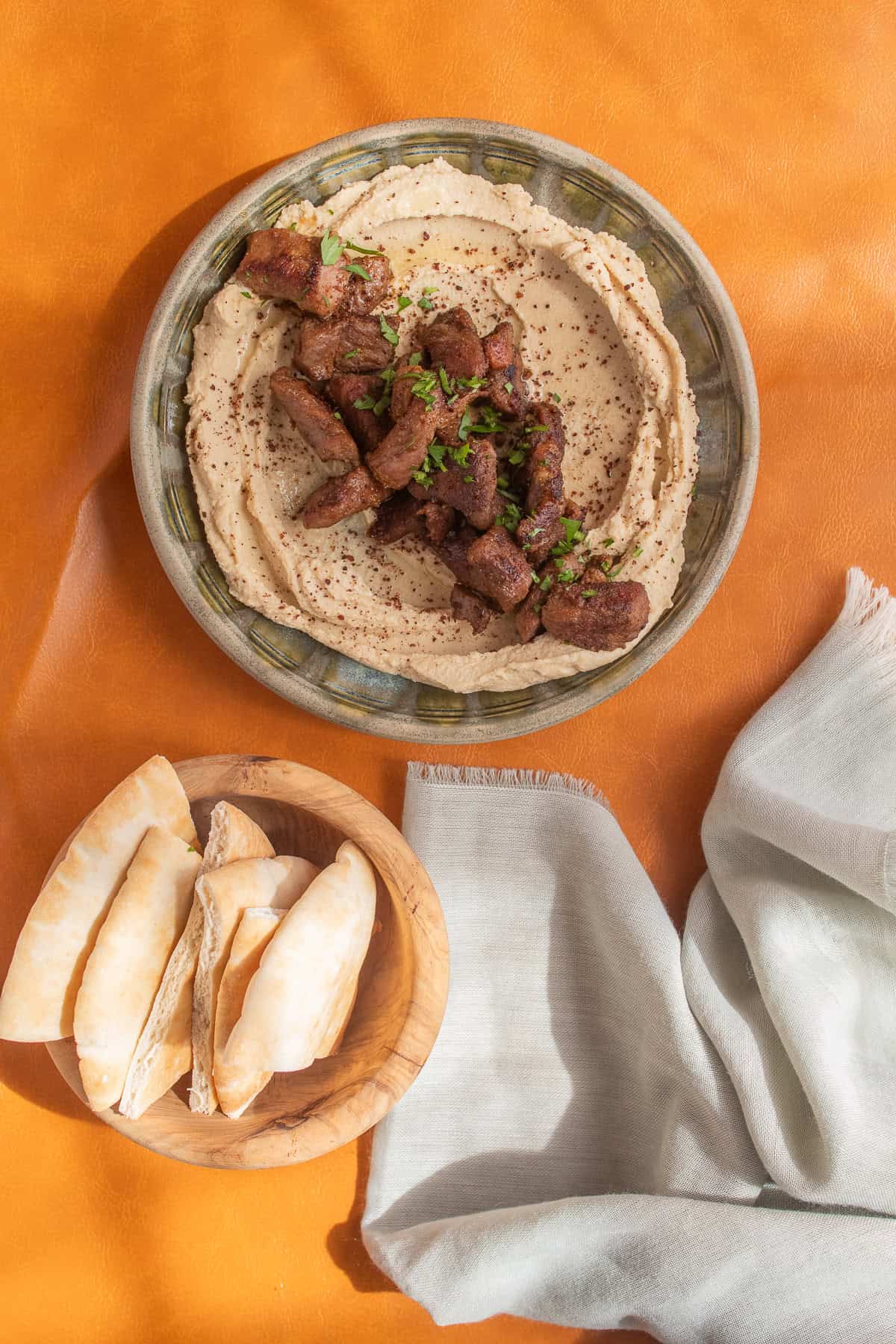 Tender spiced lamb tops a plate of smooth hummus.