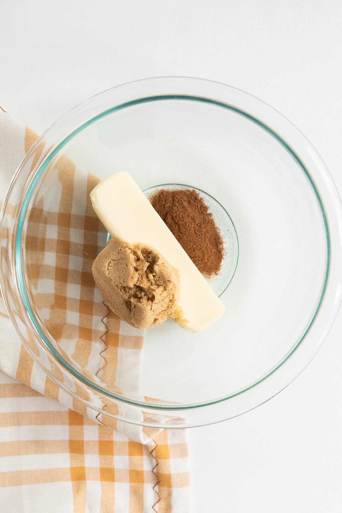 The butter, brown sugar, and pumpkin pie spice are added to a medium bowl.