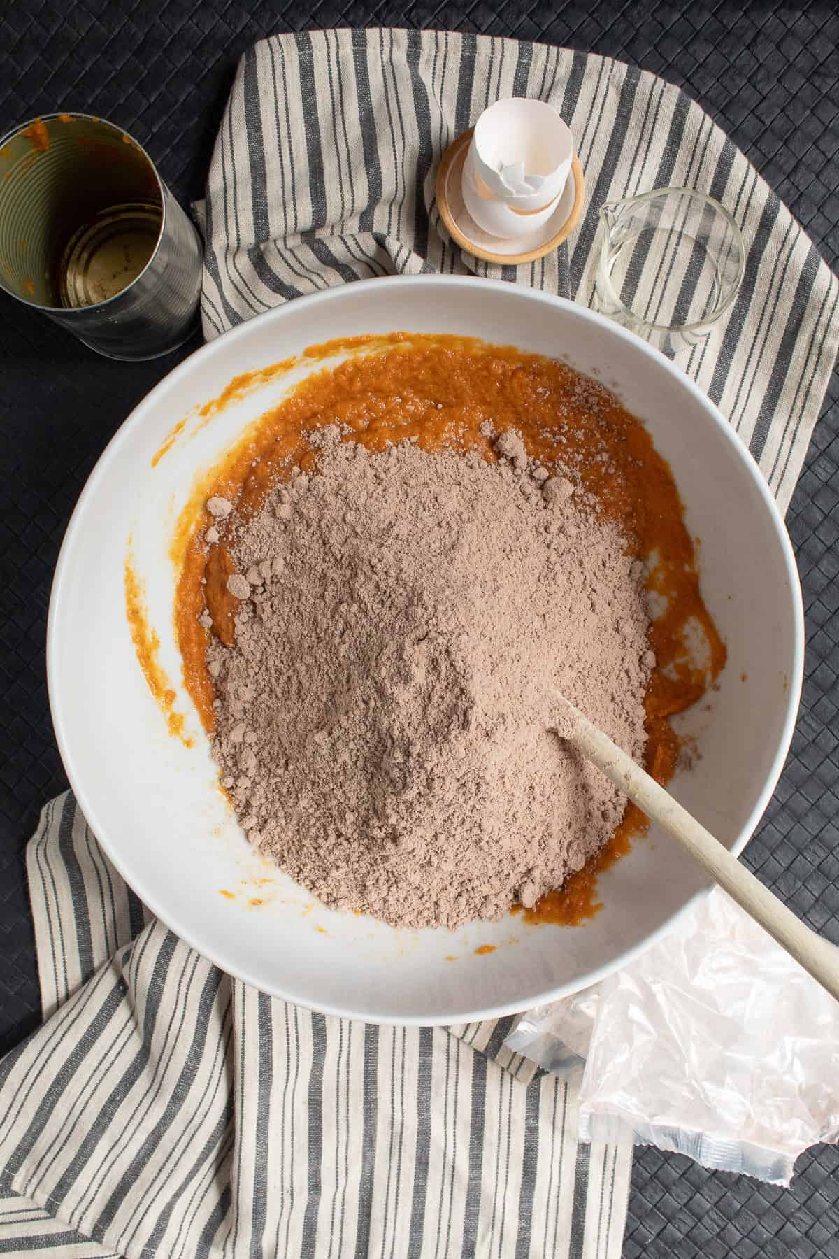 The dry cake mix is added to the wet ingredients in a large white bowl.