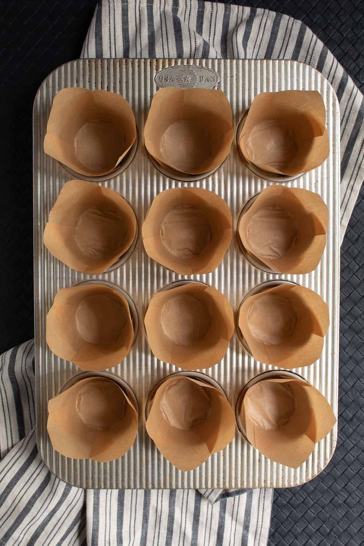 The muffin tin is lined with brown paper liners.