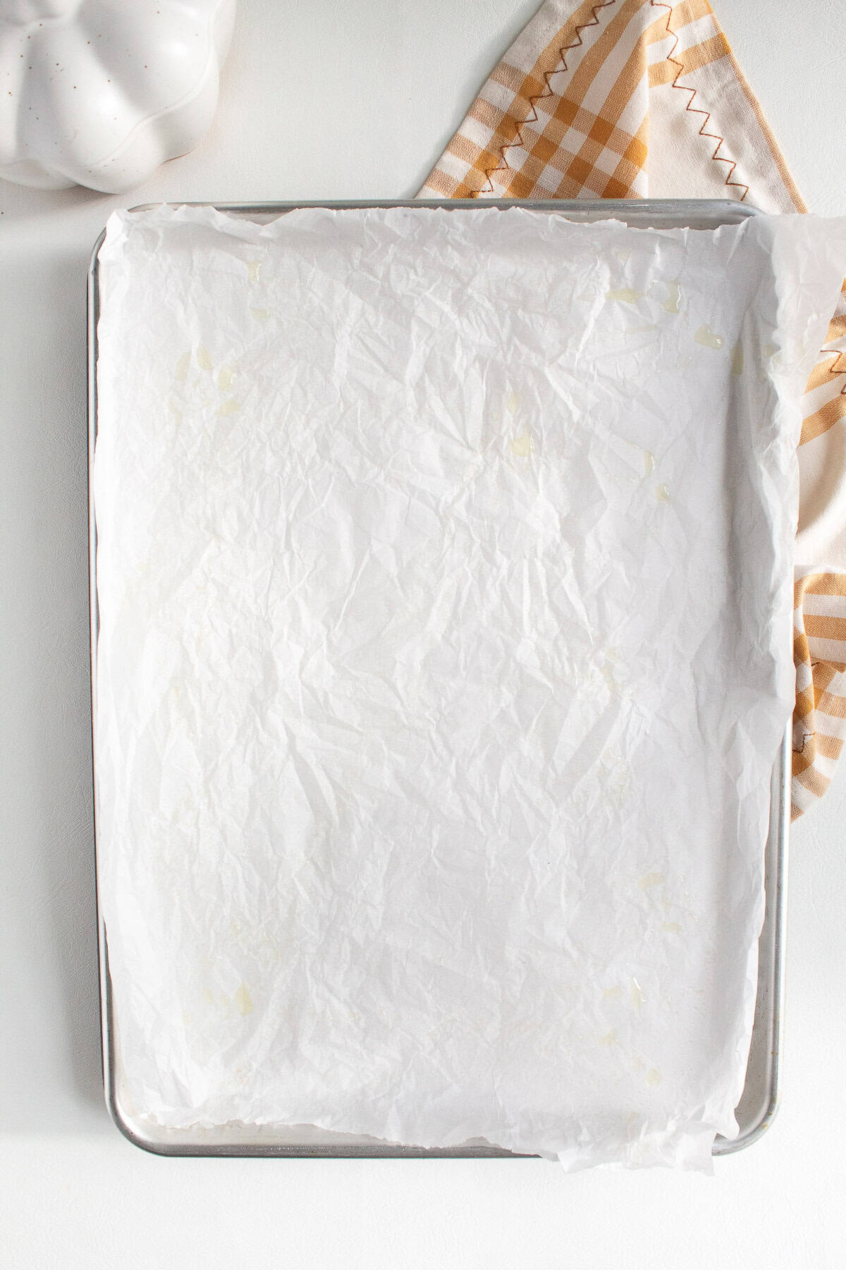 A sheet pan is lined with parchment paper and sprayed with oil.