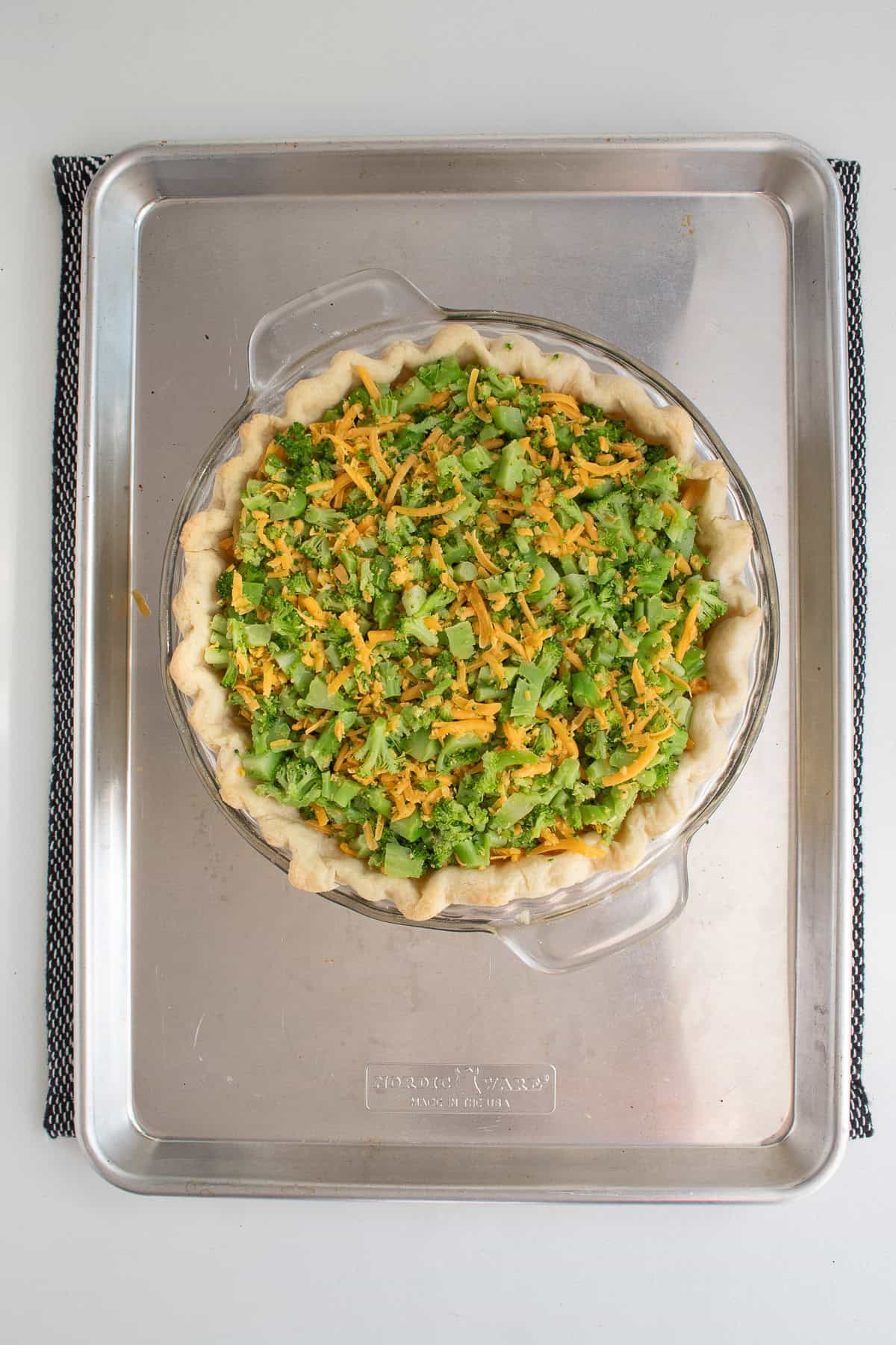 The broccoli and cheddar are piled onto the baked crust.