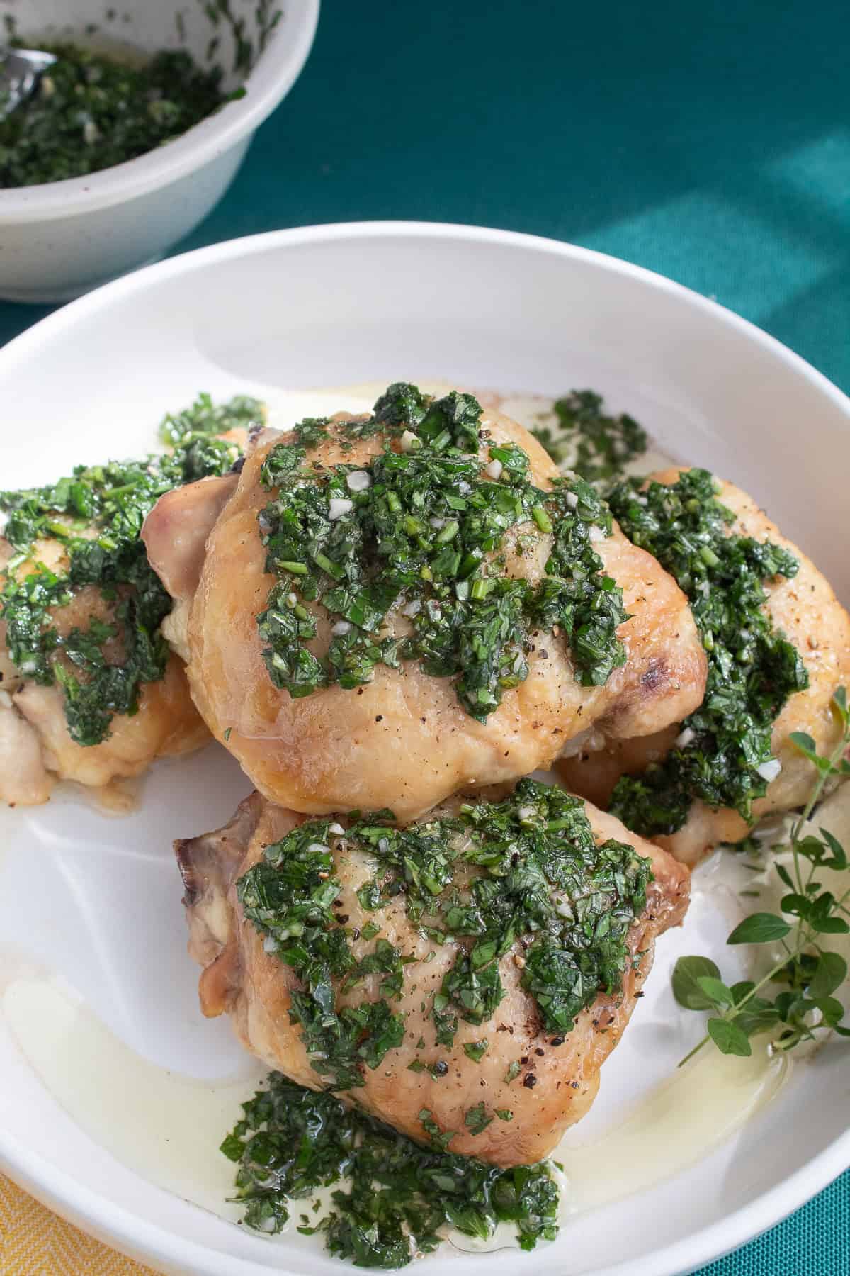 A pile of crispy roasted chicken thighs is covered in a deep green herb sauce.