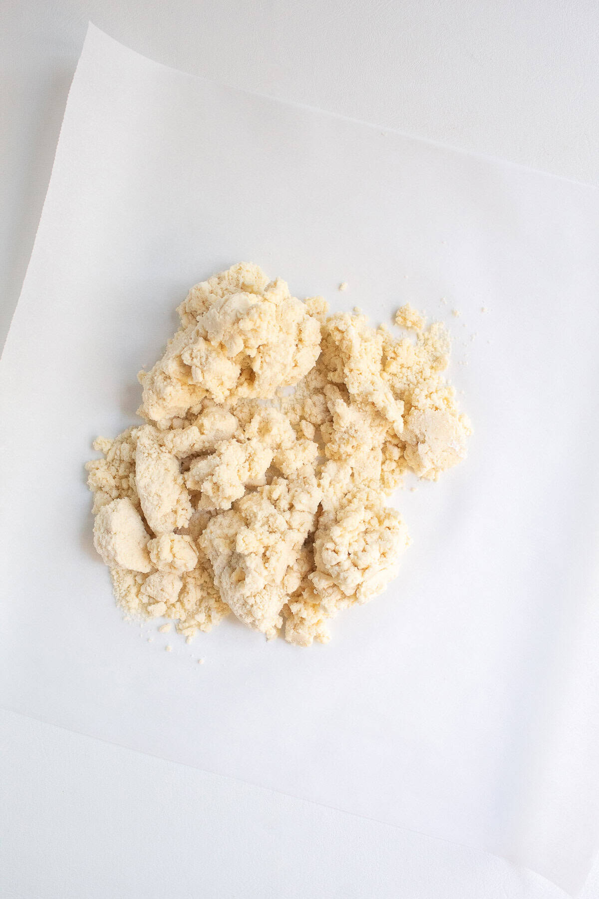 The heaps of quiche crust dough are piled onto a square of parchment paper.