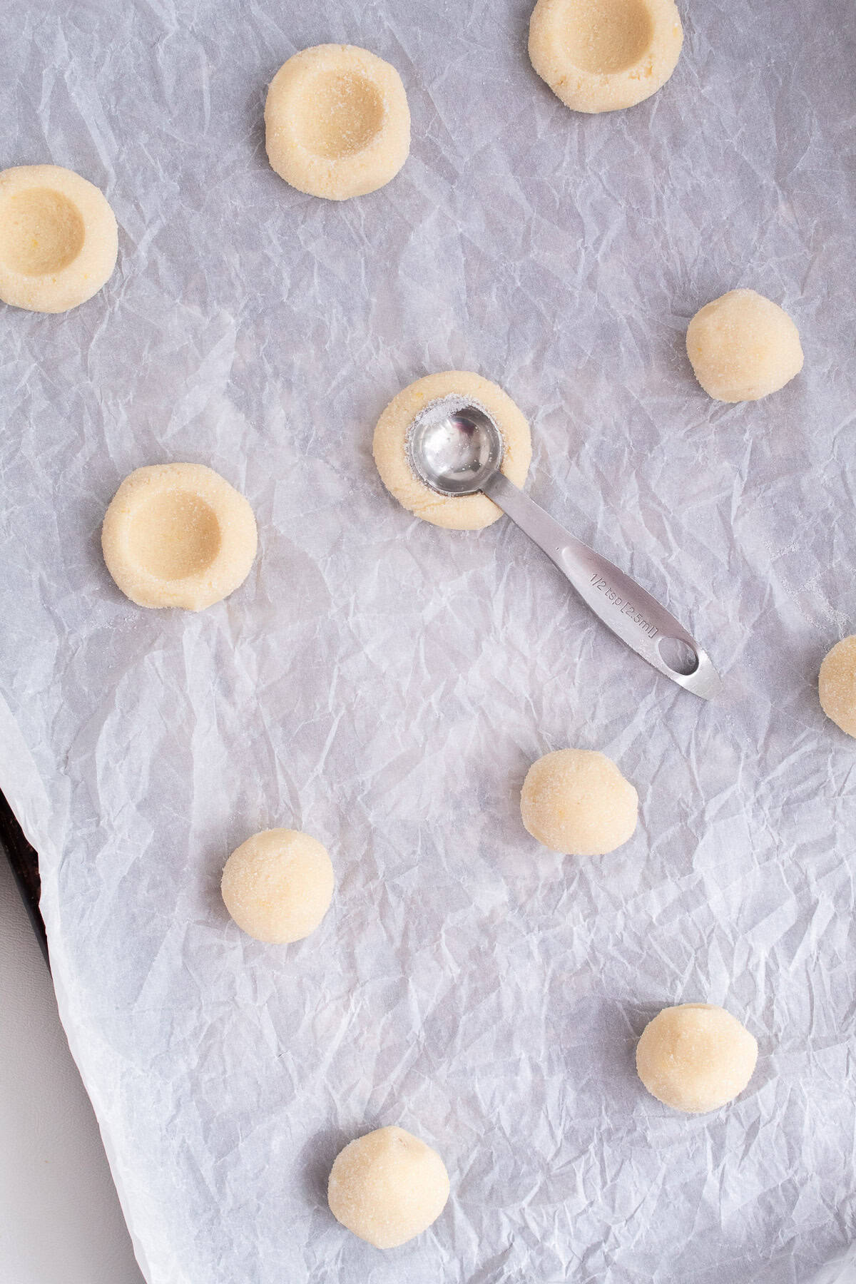 Each cookie is pressed with a sugared measuring spoon to create an indentation for lemon curd filling.
