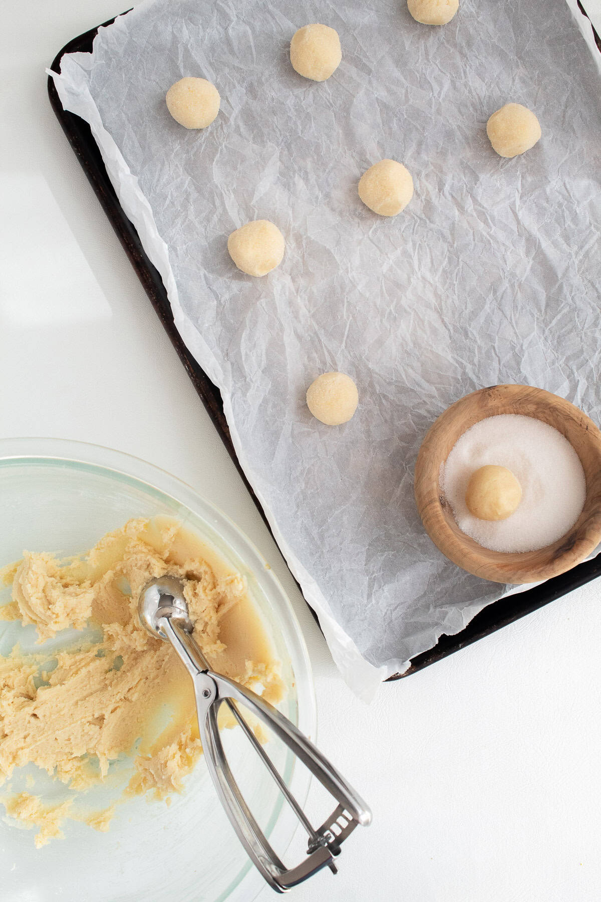 Cookie dough balls are shaped and rolled in granulated sugar before placing on the pan.