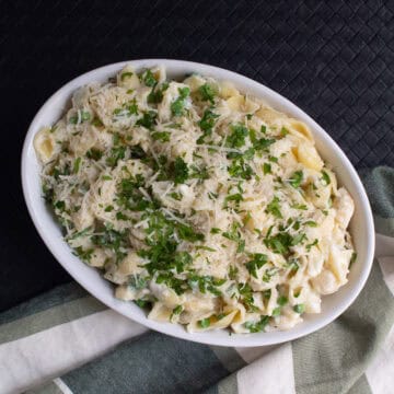 The ricotta pasta is served garnished with parsley and Parmesan cheese.