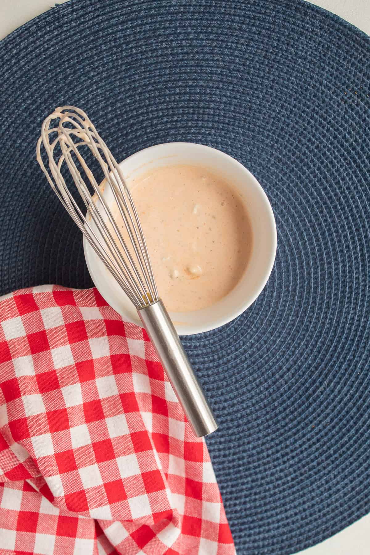 The tangy and spicy blue cheese sauce is whisked together in a white bowl.