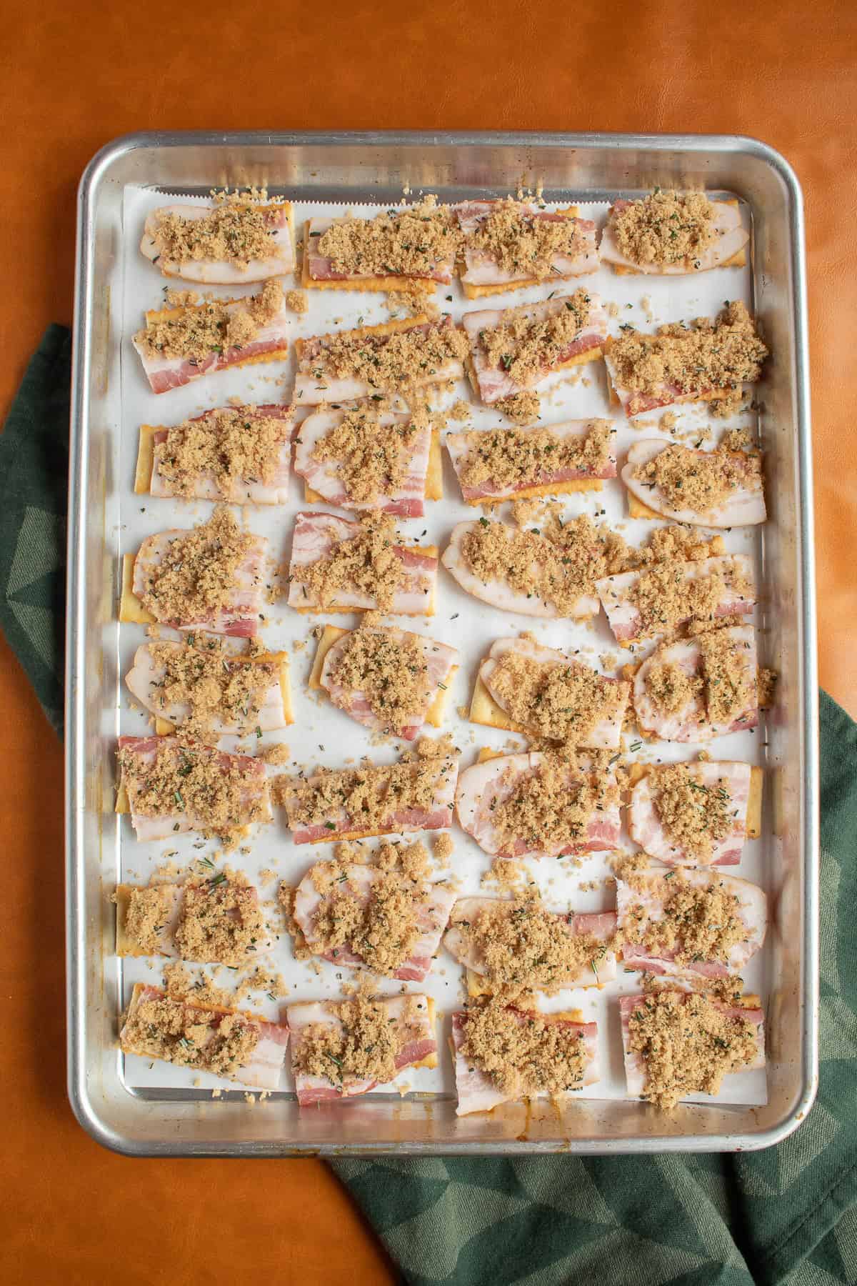 Bacon slices are sprinkled with a brown sugar, rosemary, and black pepper, mixture.
