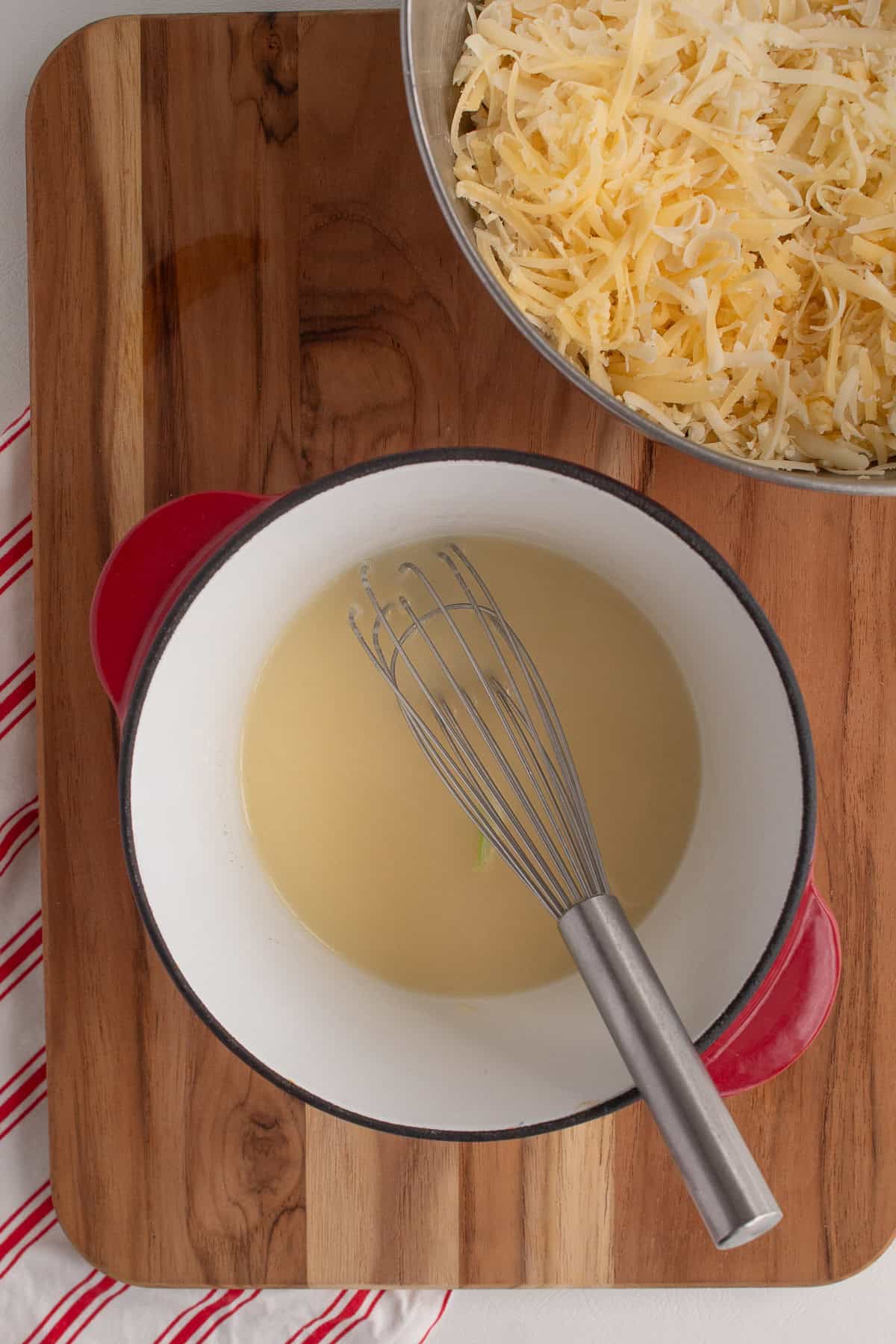 The first handful of cheese is whisked into the simmering wine.