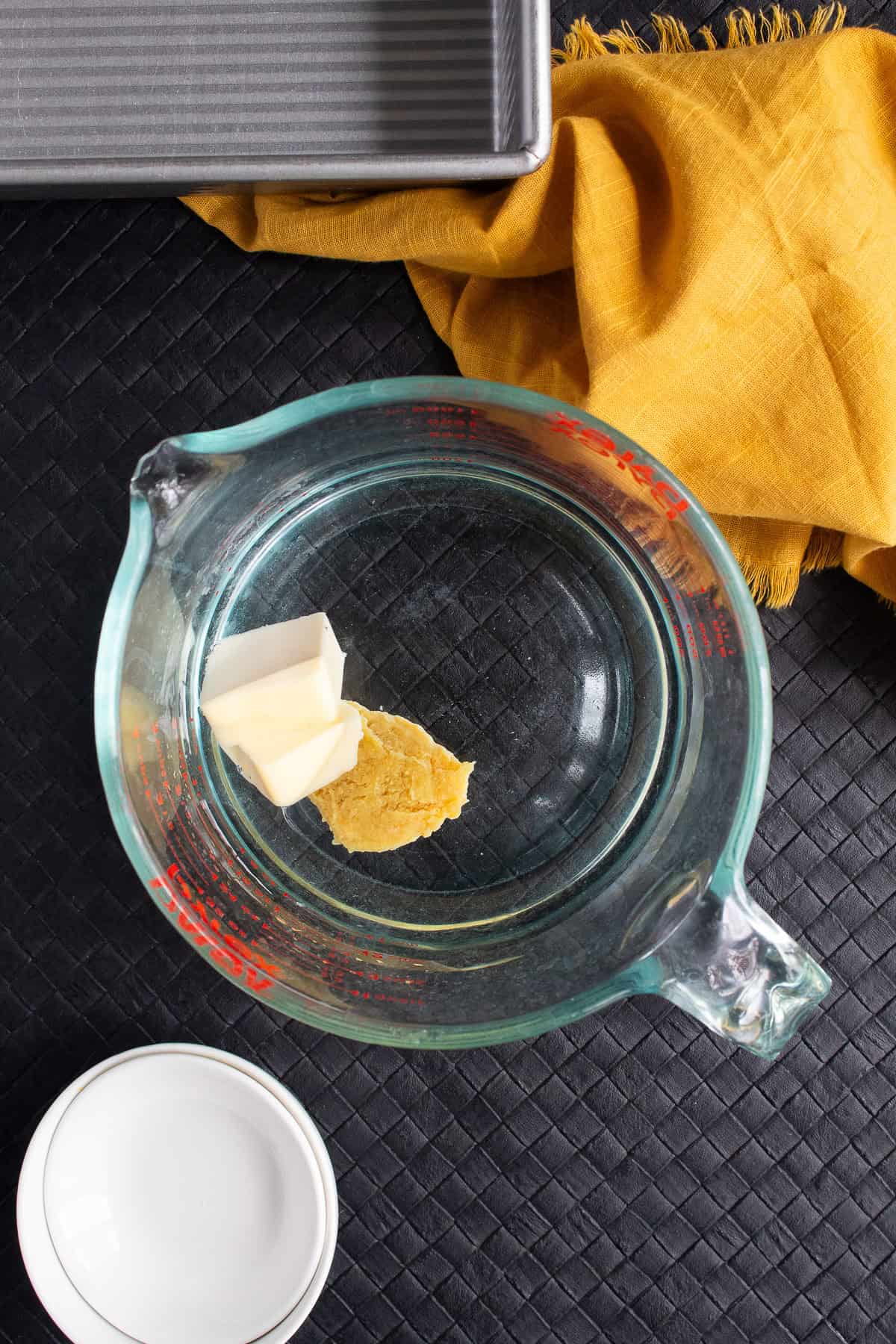 Butter and chicken bouillon are added to water in a microwaveable bowl.