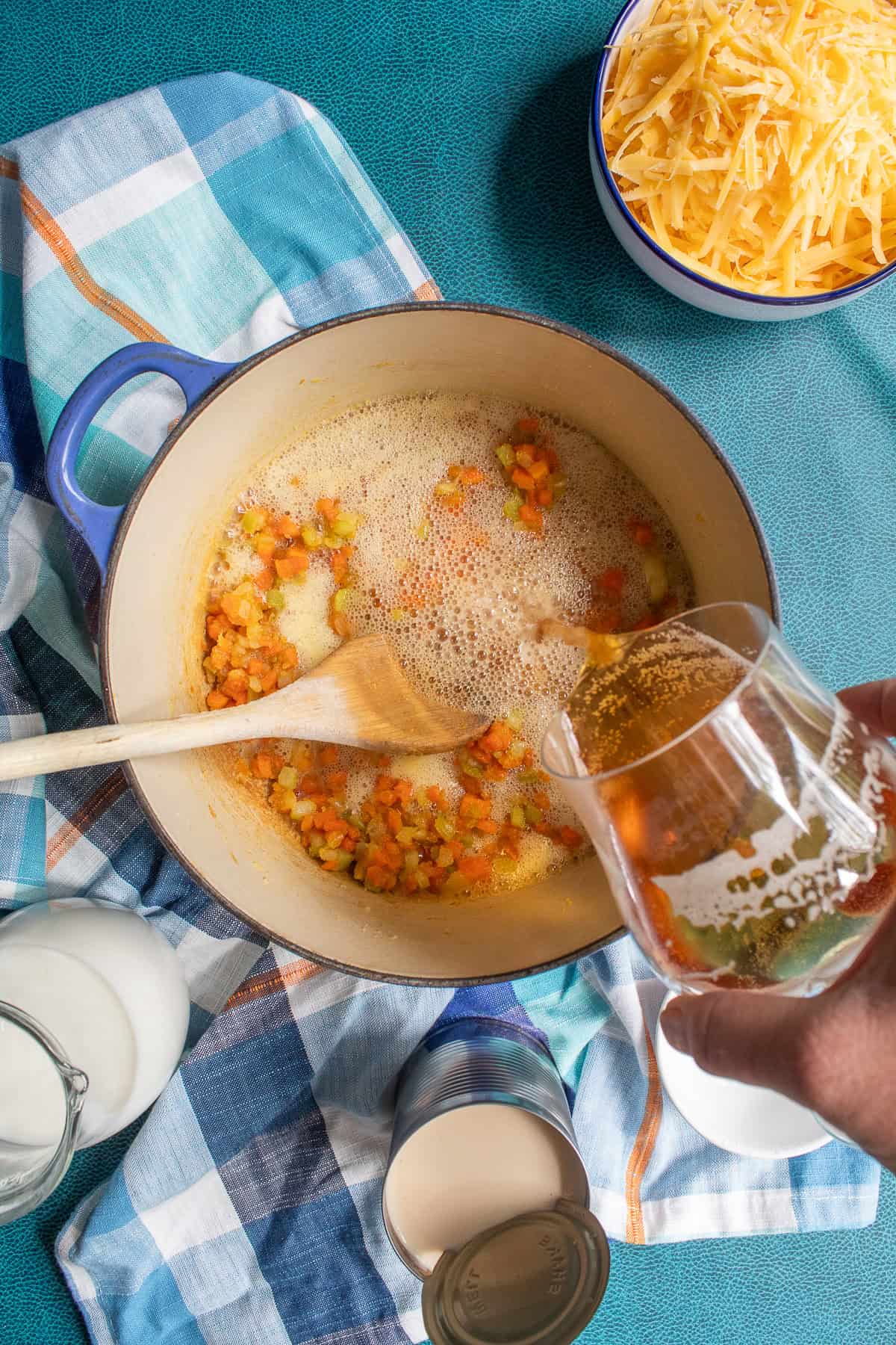 Beer is slowly streamed into the vegetable and flour mixture.
