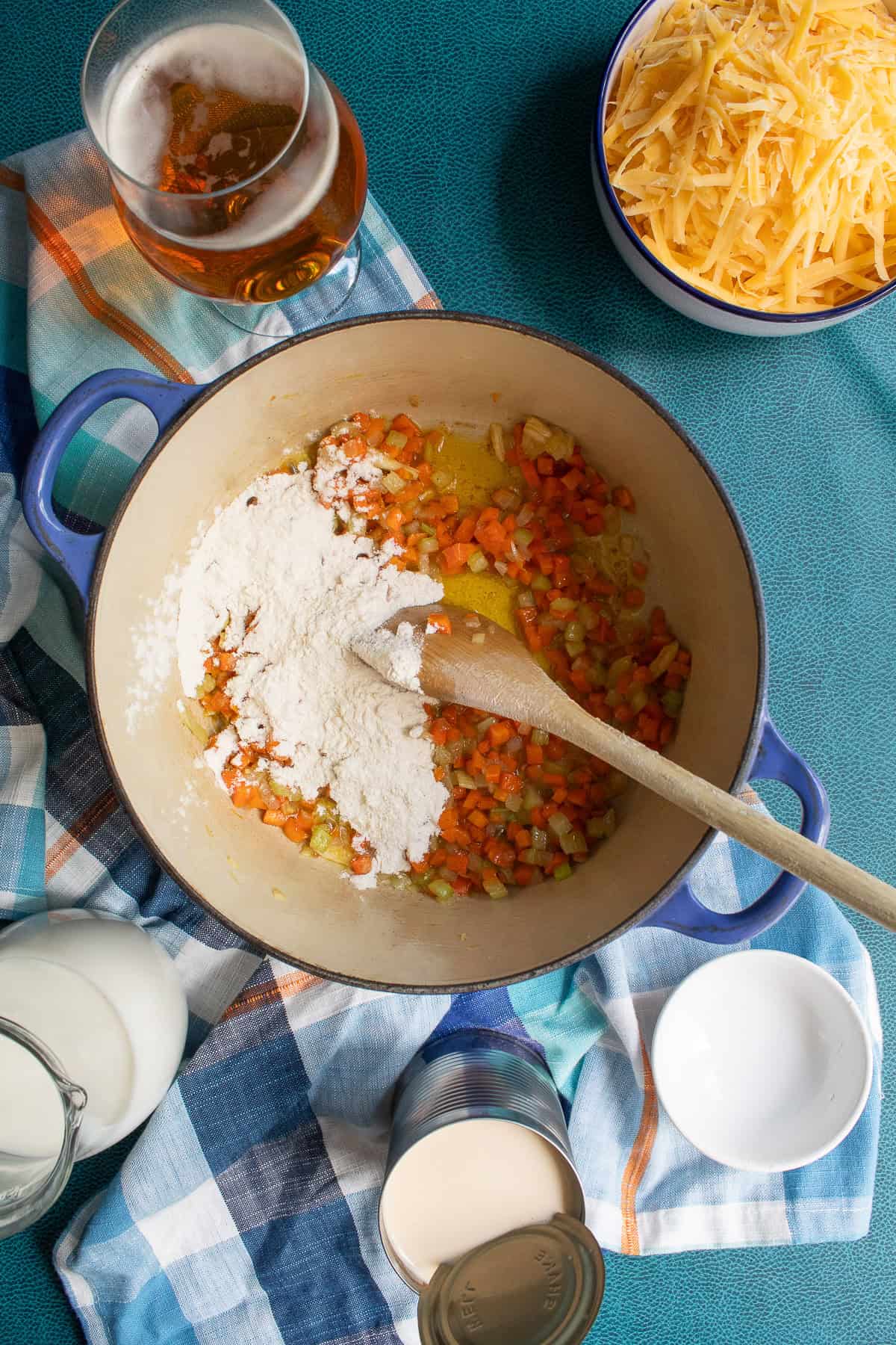 Flour is sprinkled over the sauteed vegetables in teh soup pot.