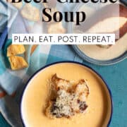 The creamy soup is displayed on a blue surface and is topped with pretzel bread croutons and additional shredded gouda cheese. A white text box at the top of the image contains the words, "beer cheese soup" and "plan. eat. post. repeat."