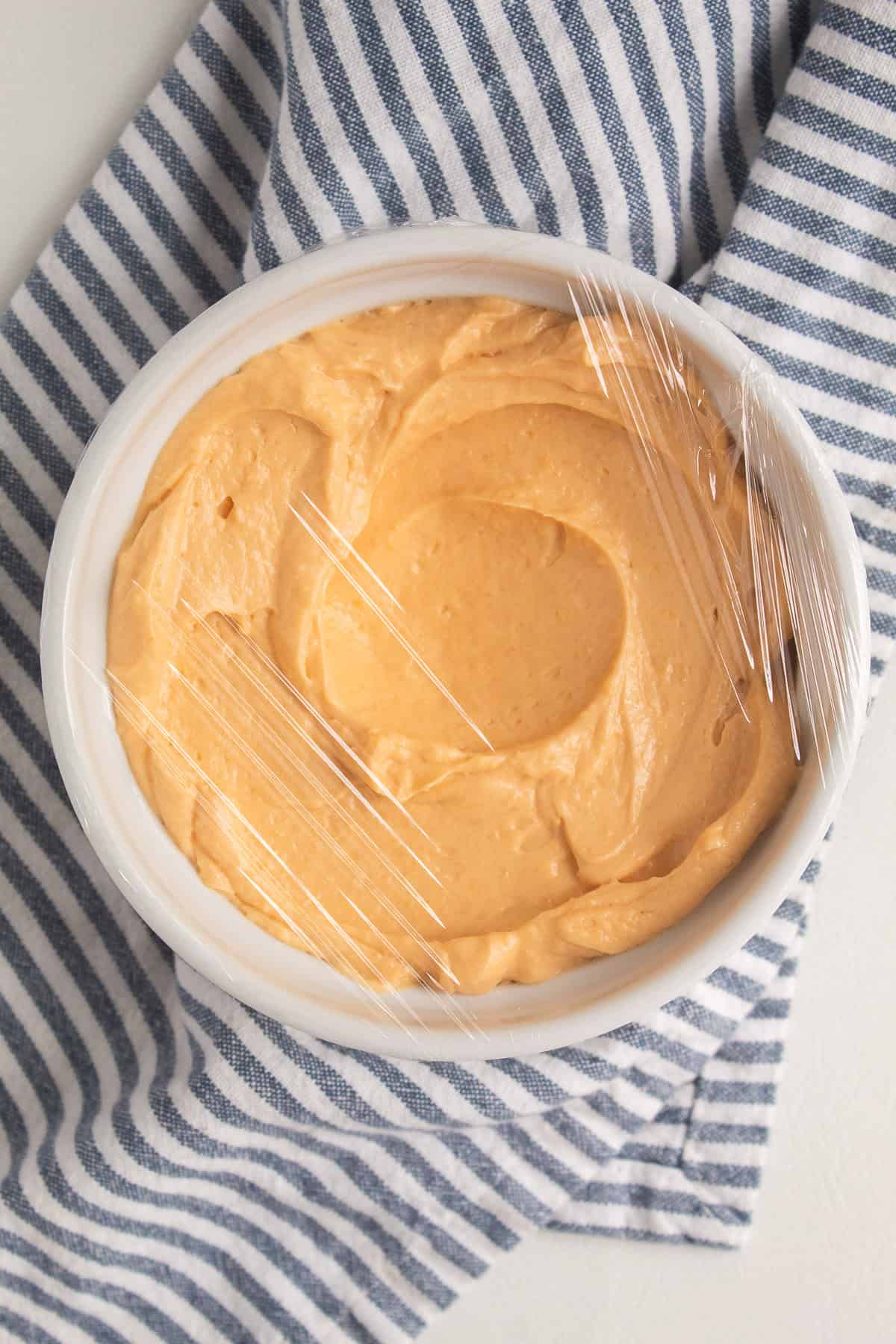 For a firmer texture, the cheese spread is covered with plastic wrap and chilled in a white bowl.